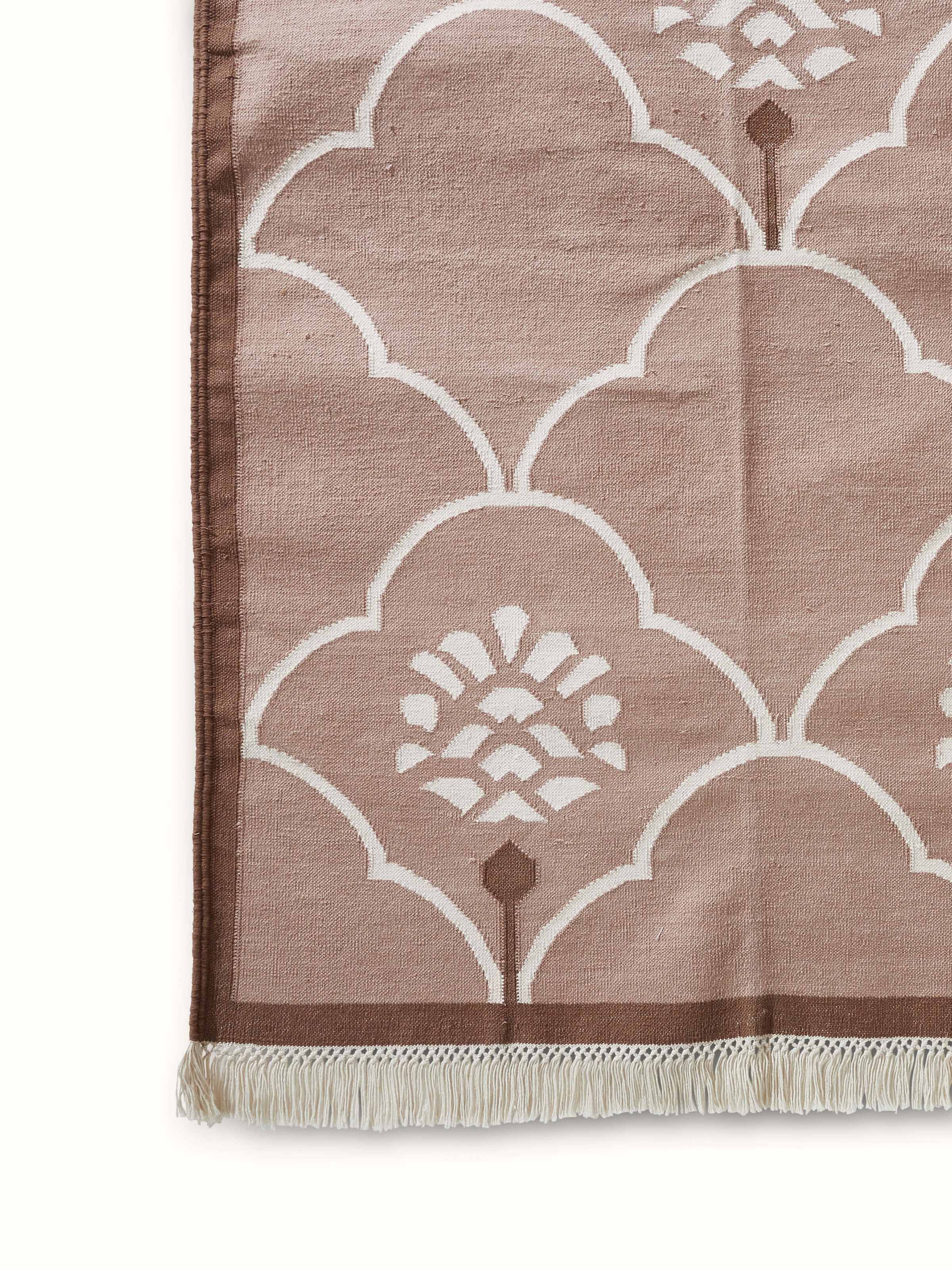 Lifestyle shot of Stylised floral beige lawan cotton panja dhurrie in a home setting