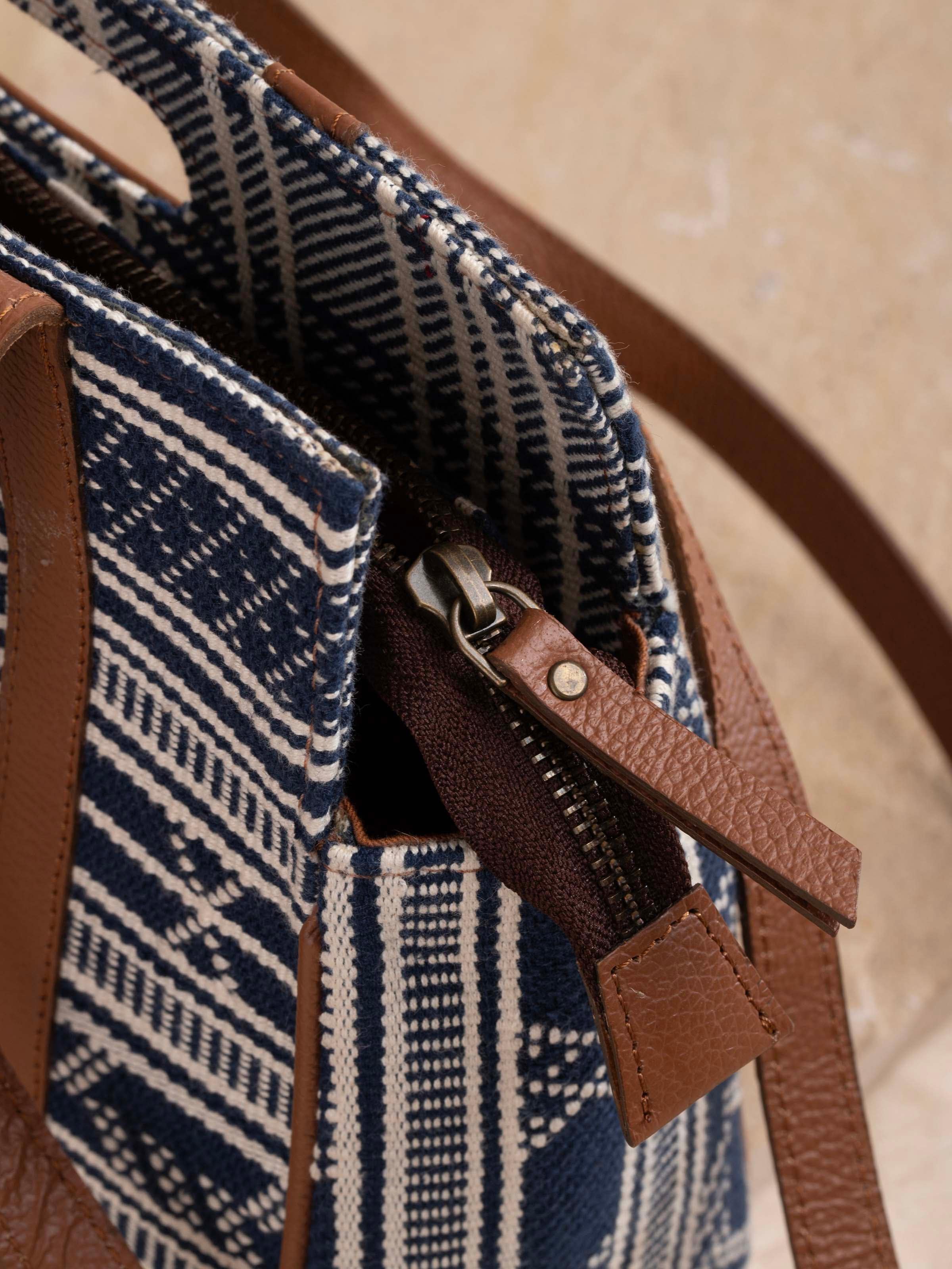 Model holding textile sling bag with strap detailing and traditional weave.