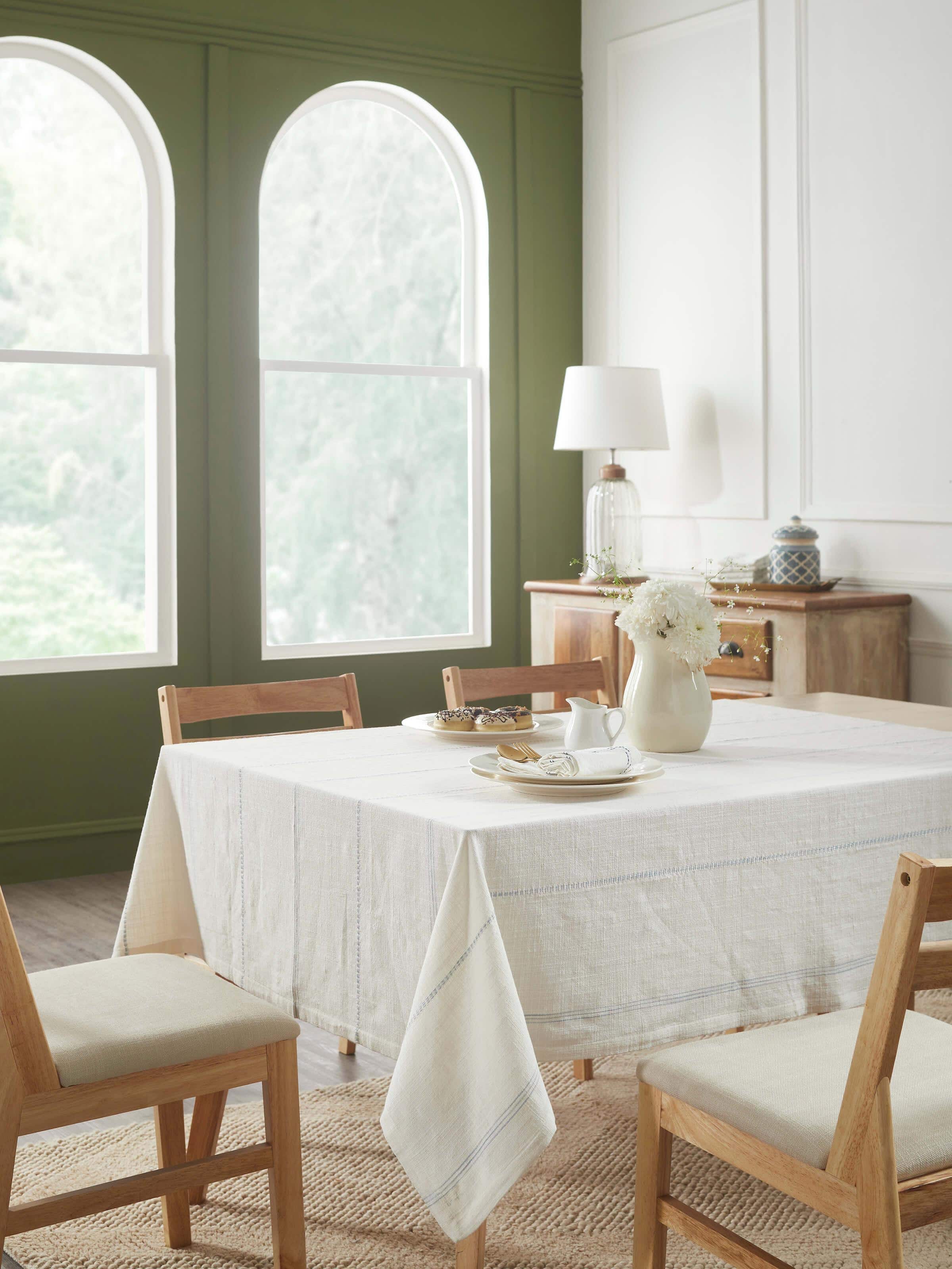 Lifestyle view of Arth light blue stripe cotton handloom table cover styled on dining table with crockery and chairs.