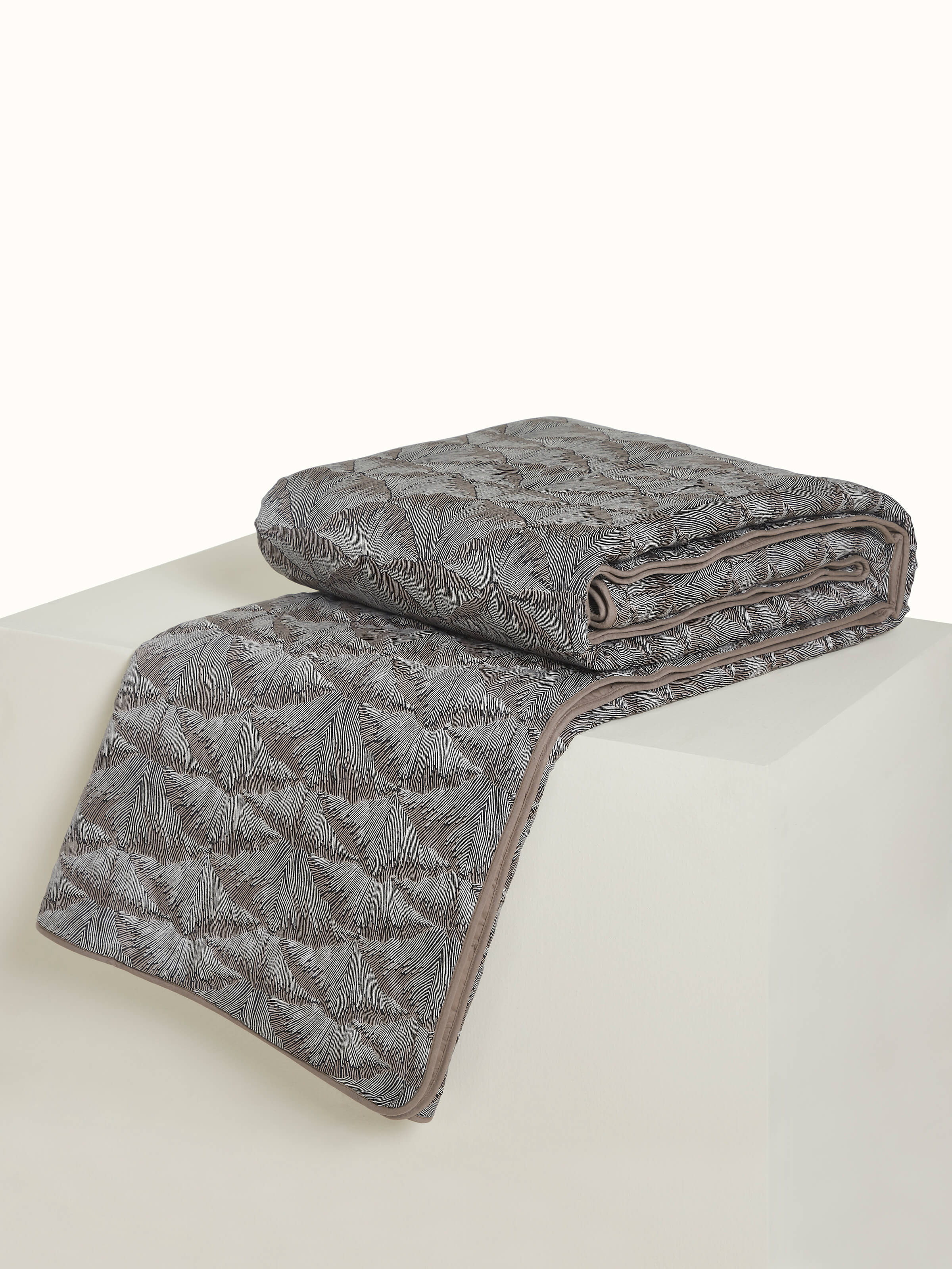 Angled view showing the intricate Sanganeri block print on Parvat brown silk quilt.