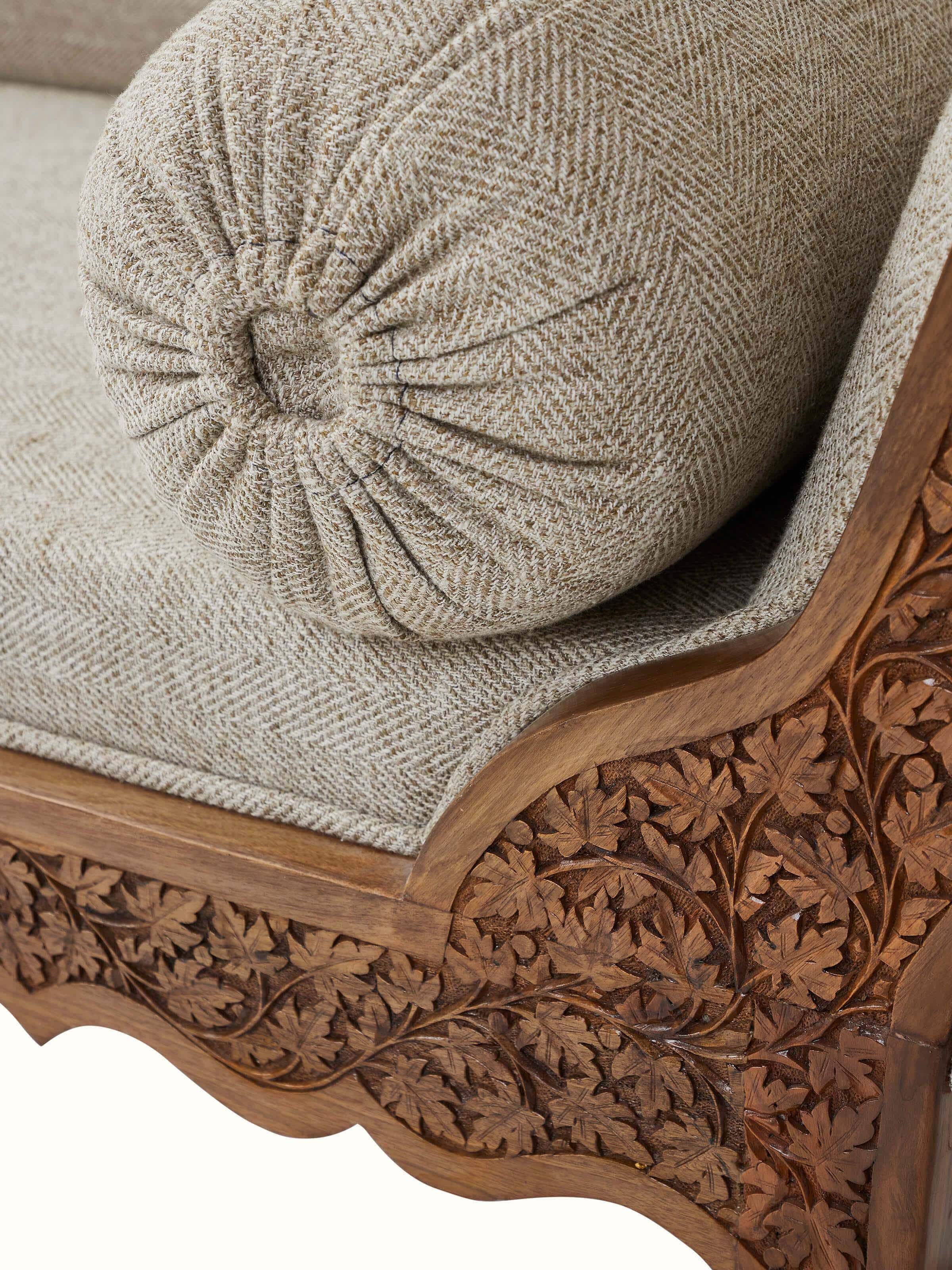 Angled view of the handloom fabric upholstered carved walnut wood daybed, showcasing the overall design and craftsmanship
