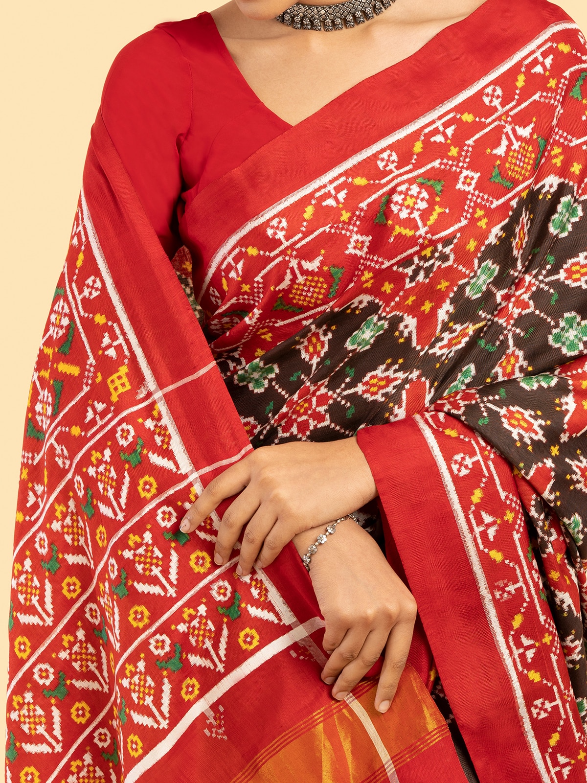 Detailed view of brown silk patola saree’s border and draping style