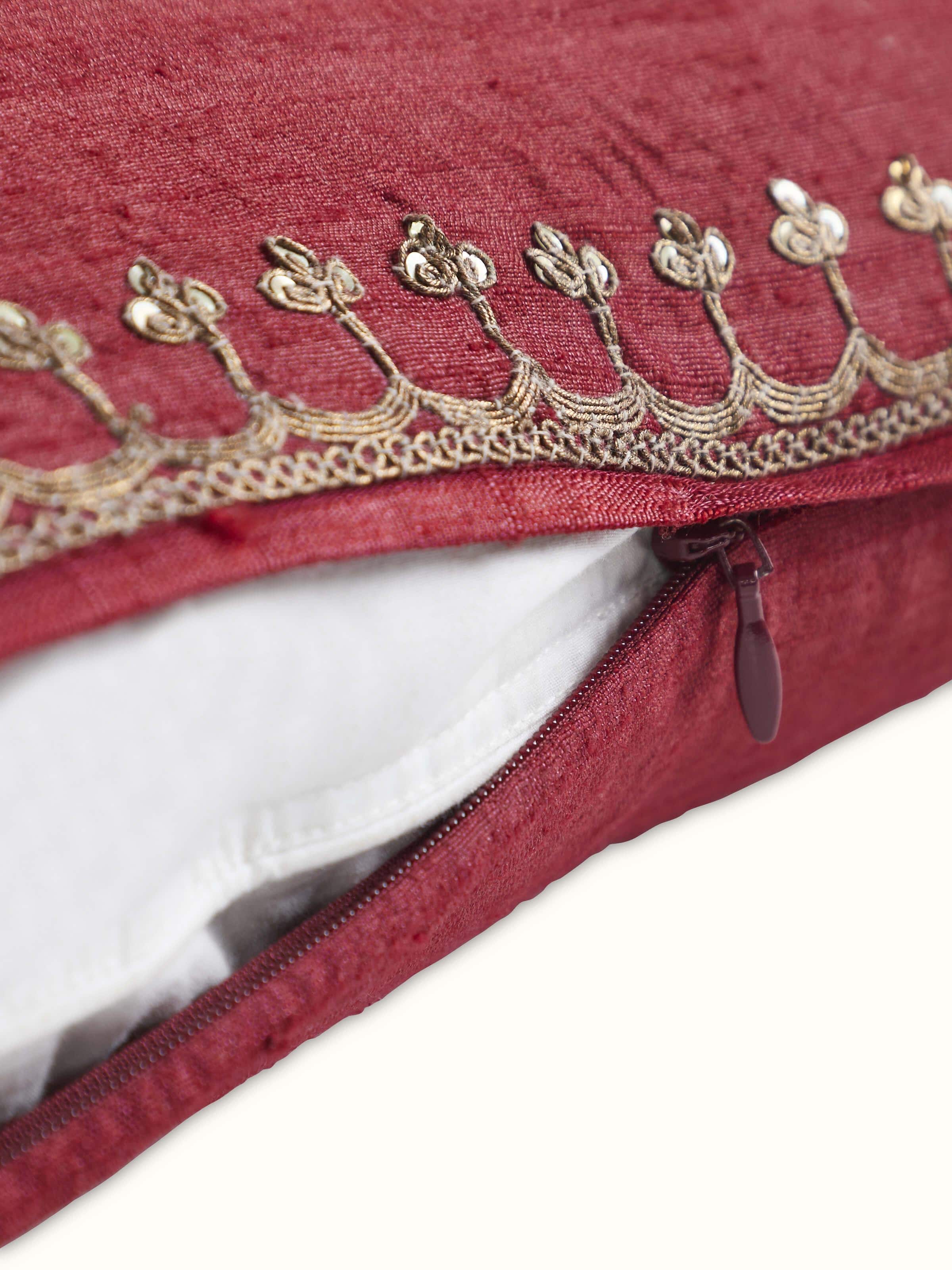 Angled view highlighting intricate zardozi embroidery on maroon silk cushion border