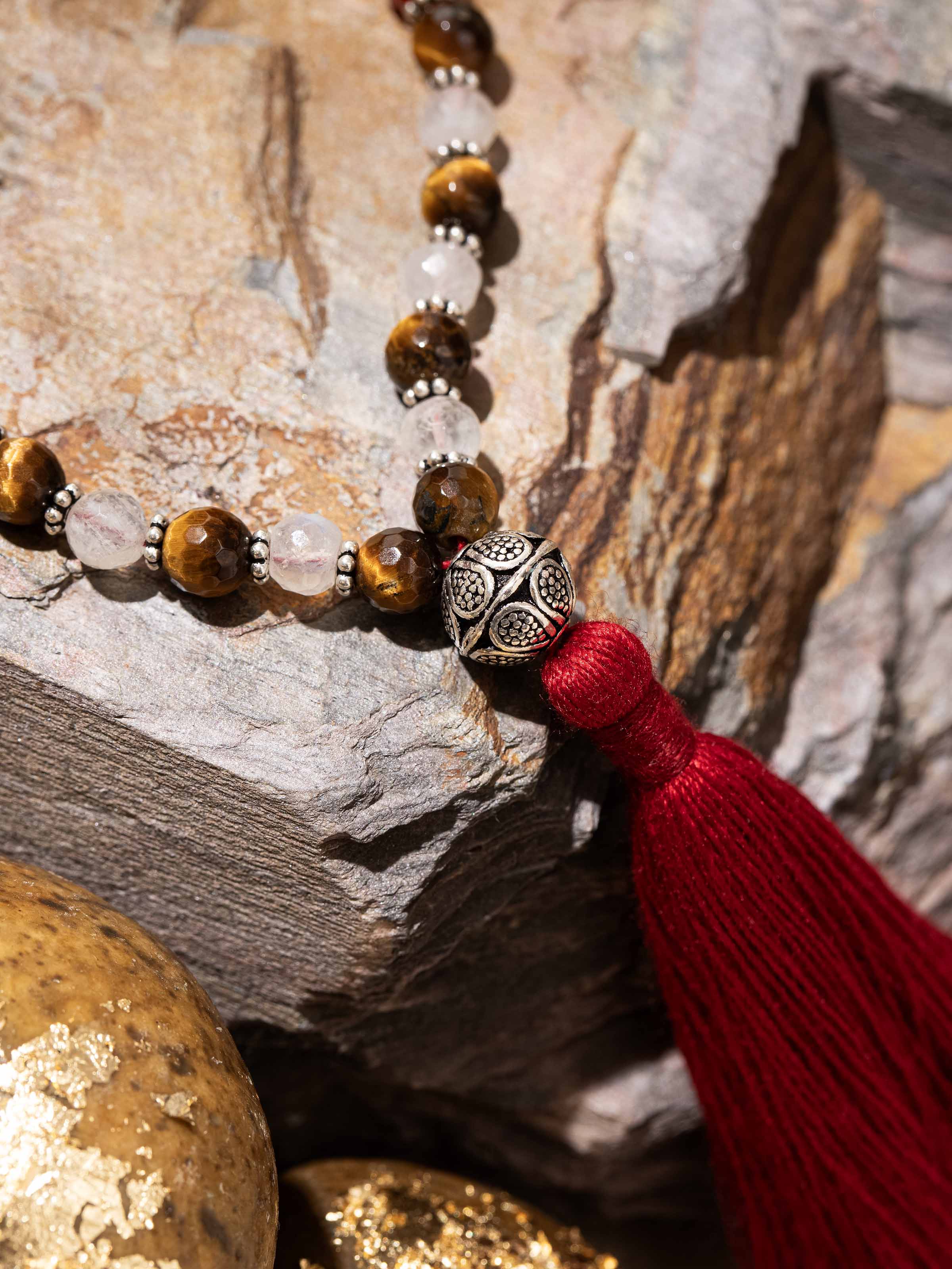 Close-up of gemstone mala with Carnelian, Quartz, and Tiger Eye in natural light
