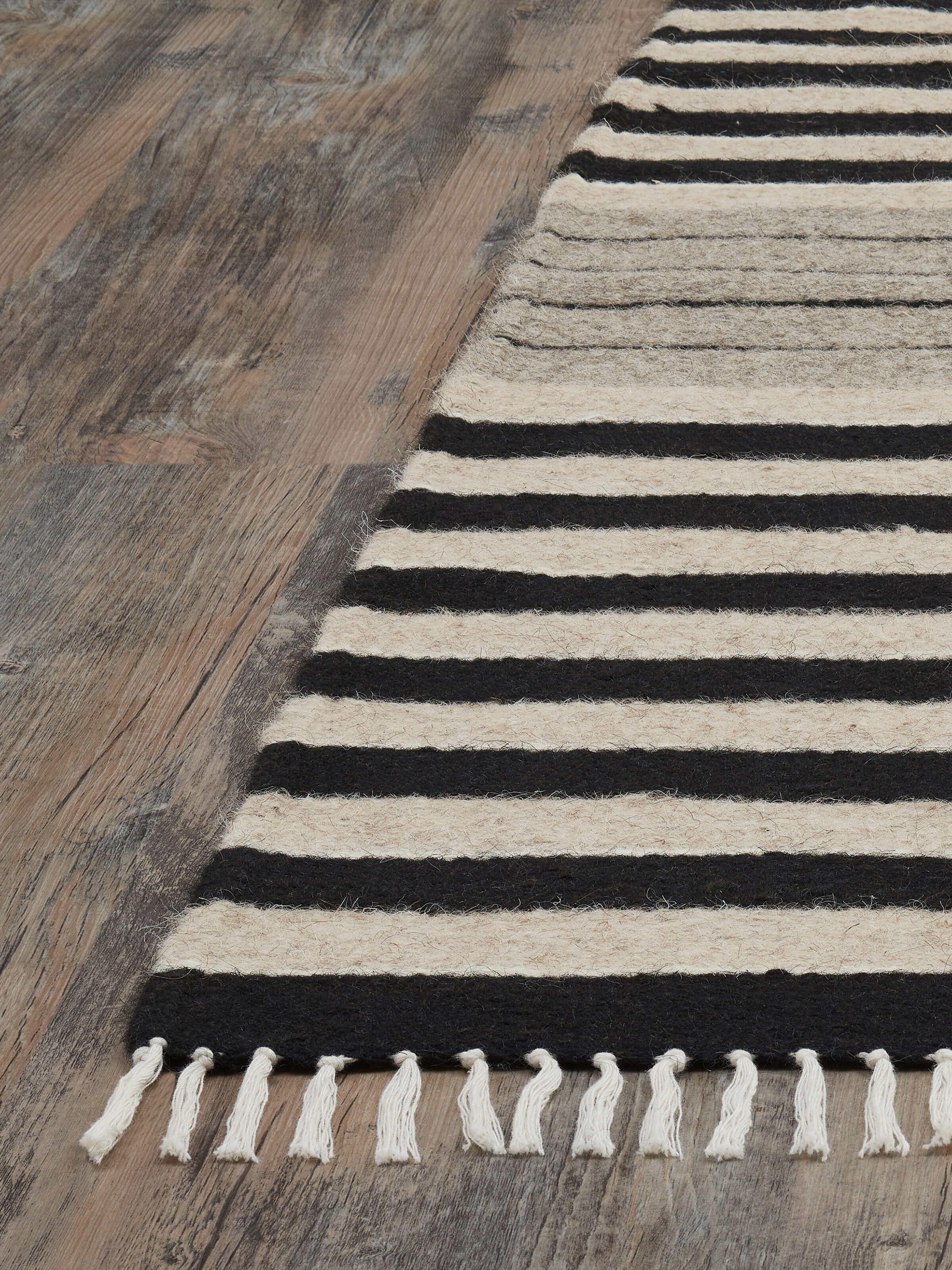 Angled view of Nomad Stripes Black Beige Jawaja Wool & Cotton Handloom Dhurrie (3x5 ft) displaying the dhurrie’s size and stripe design