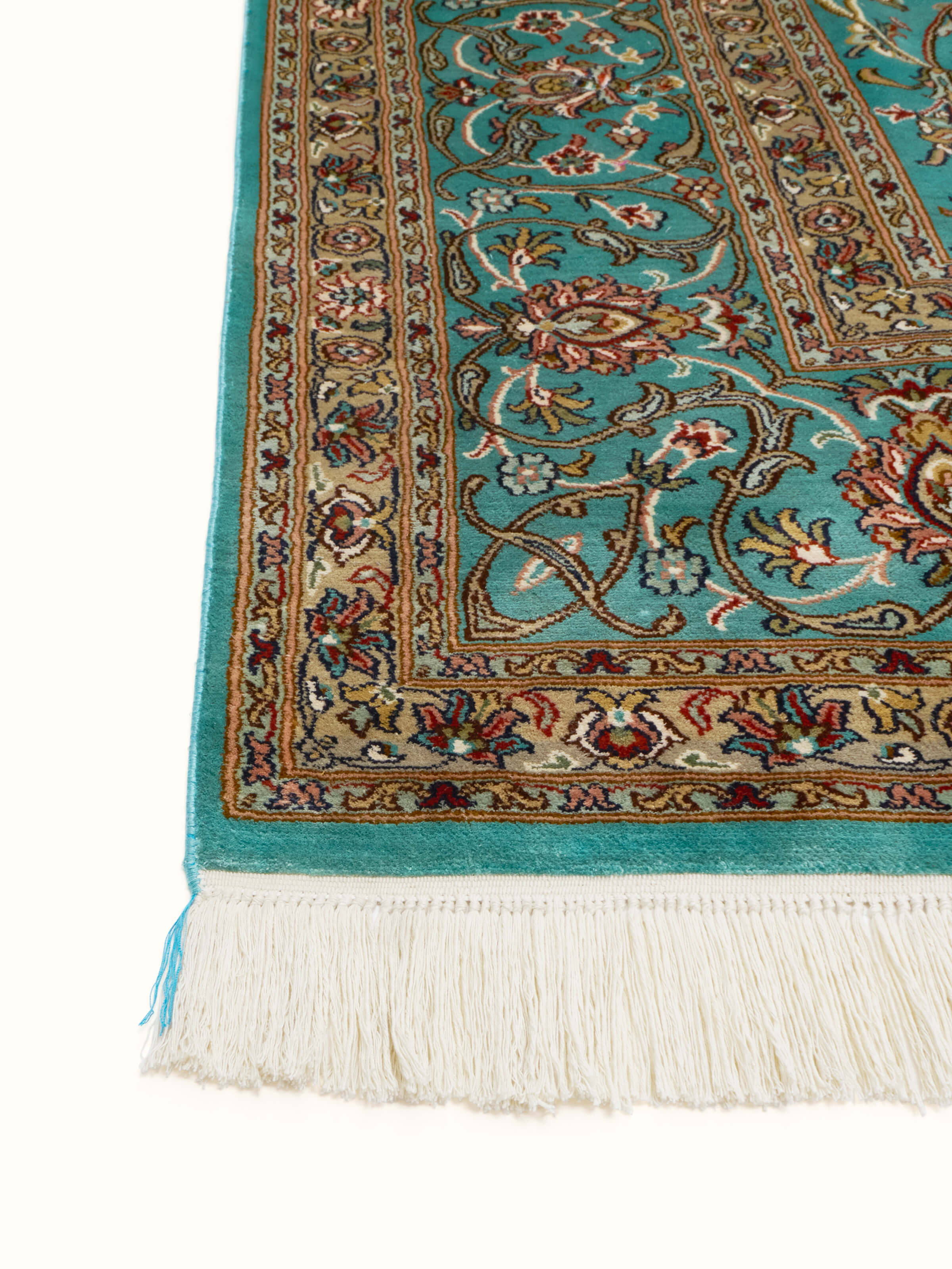 Angled view of blue Tabriz carpet showcasing its ornate border and silk texture