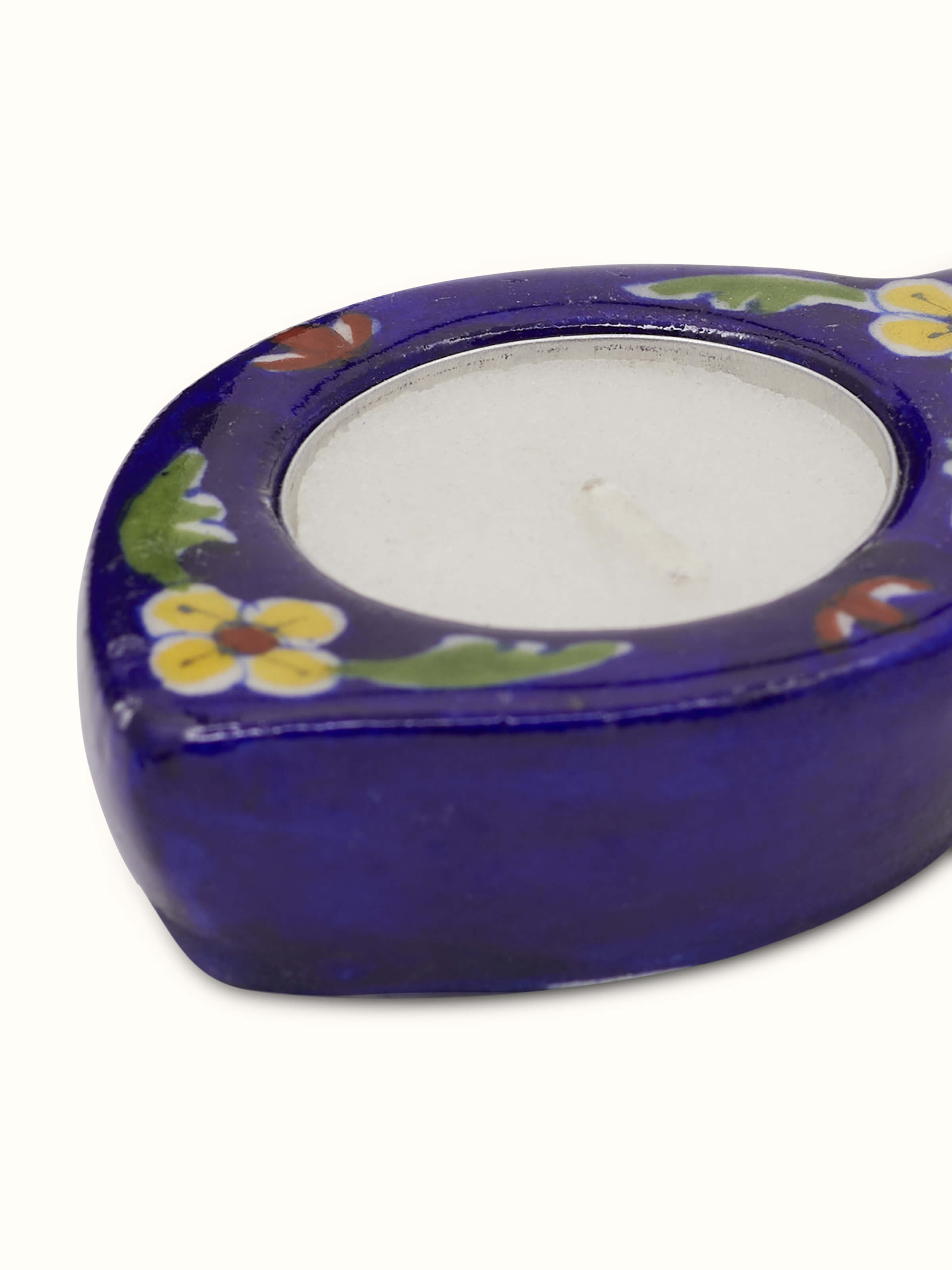 Detail close-up of blue pottery tea light holder showing glaze and artwork