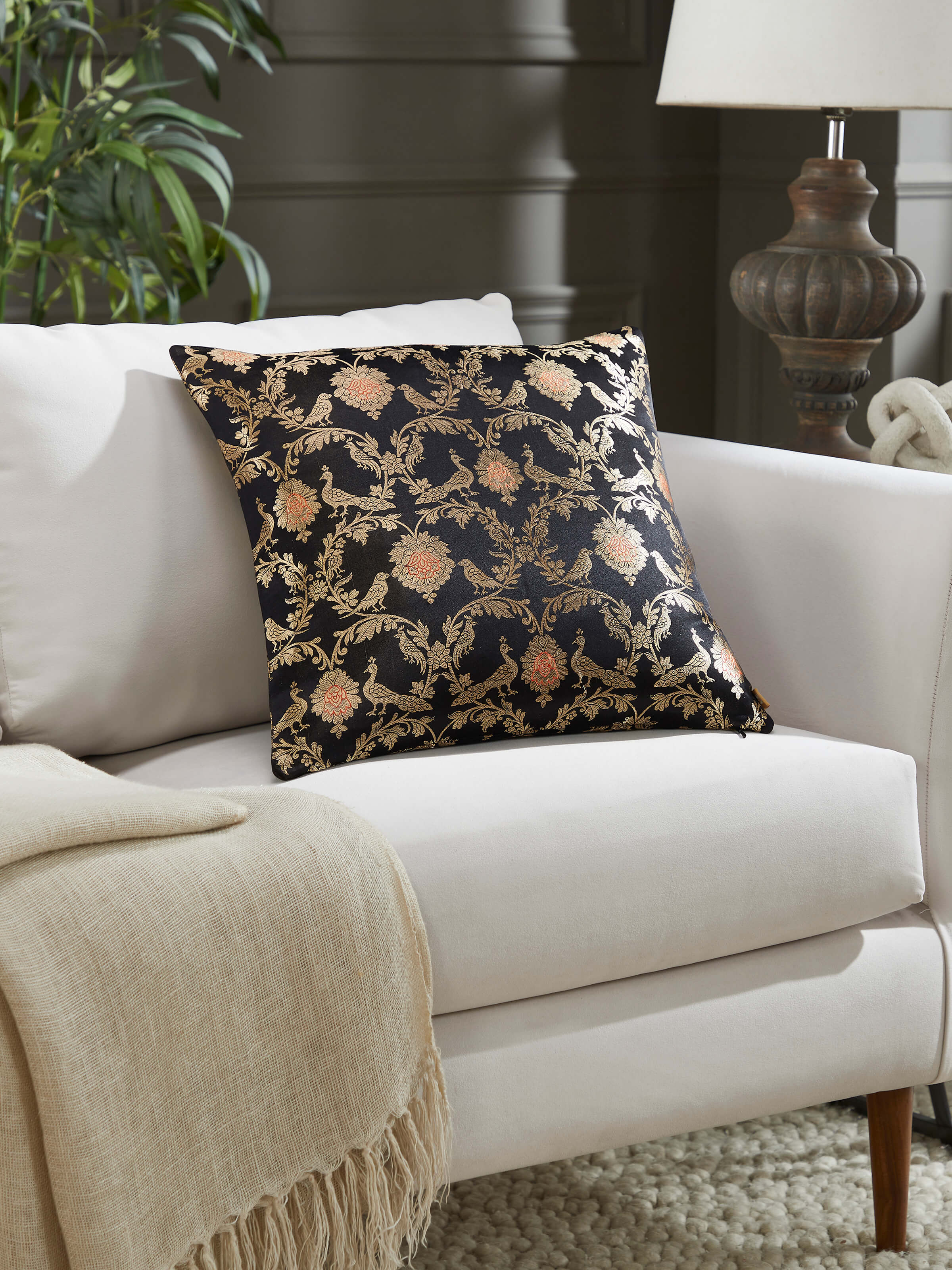 Lifestyle image of black Banarasi silk cushion on a classic sofa setup