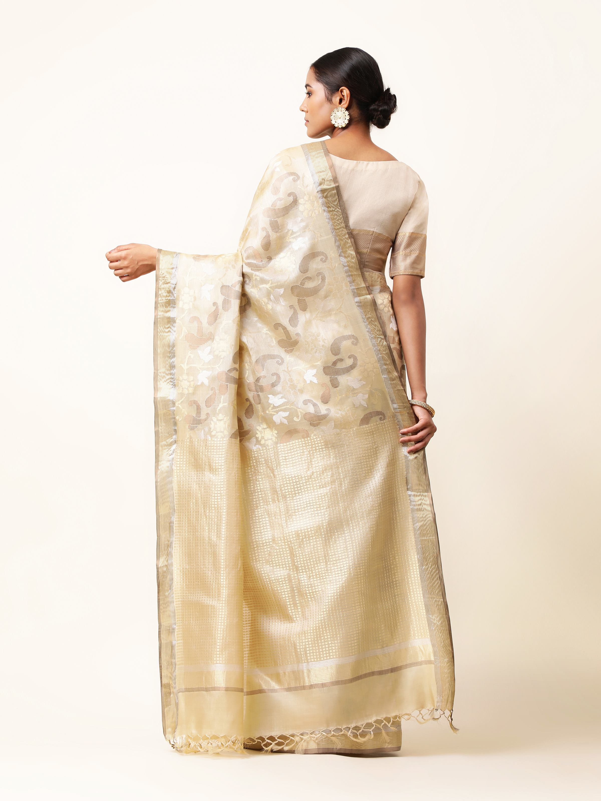 Back view of beige tussar silk saree revealing delicate pallu design and drape