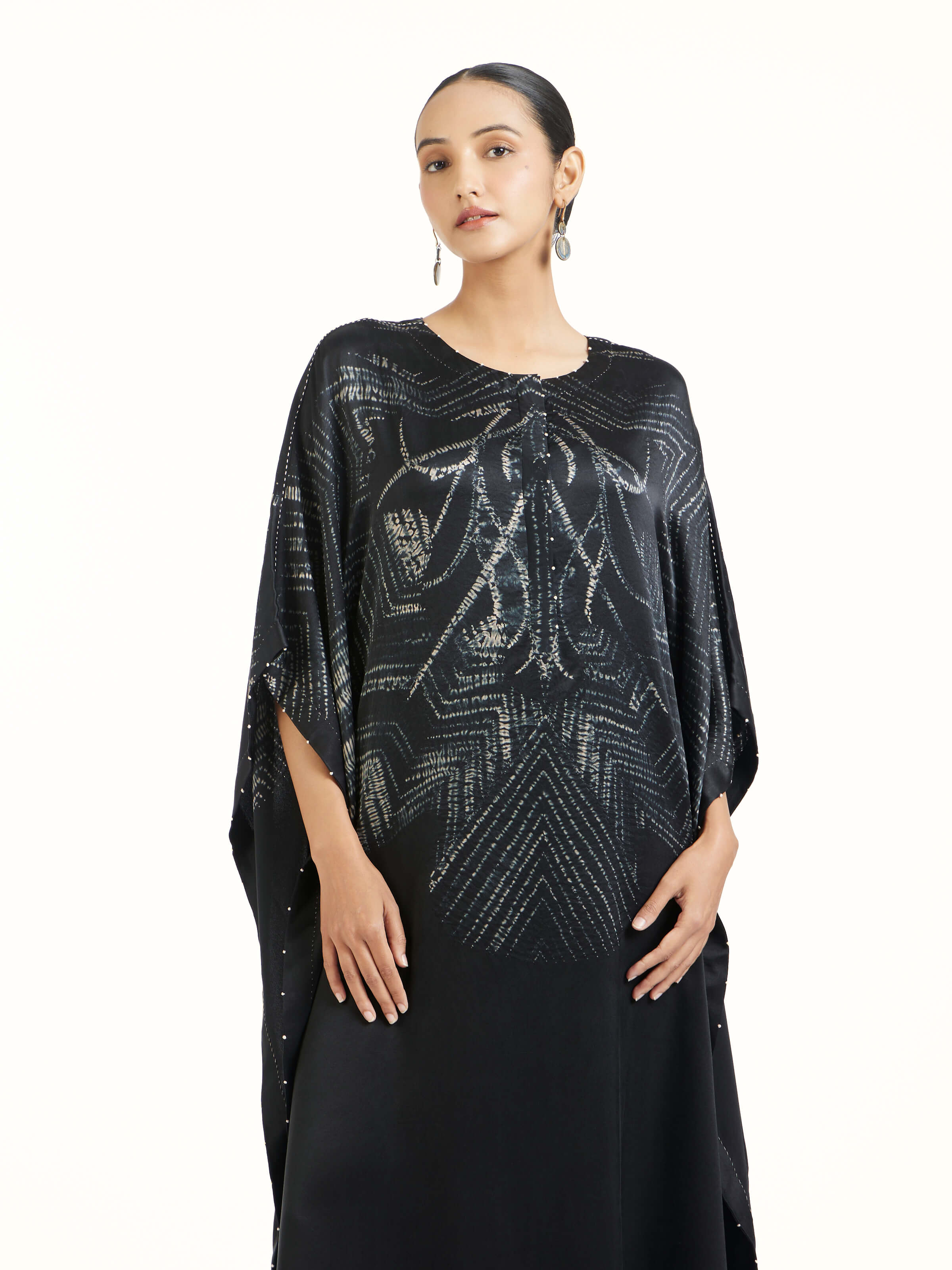 Angled view of black satin shibori kaftan highlighting shibori patterns
