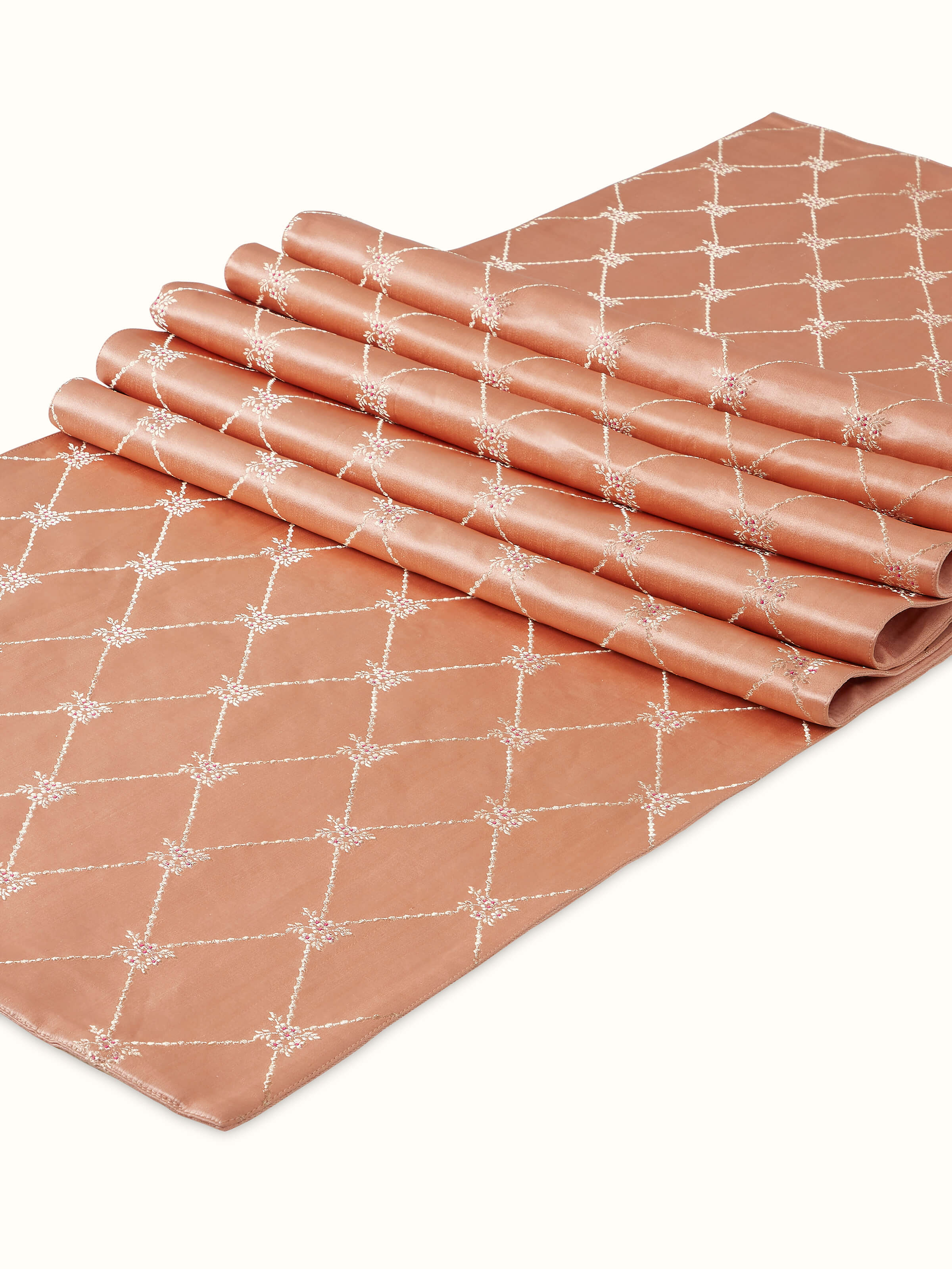 Angled view of silk bed runner revealing its glossy peach finish and woven detail.