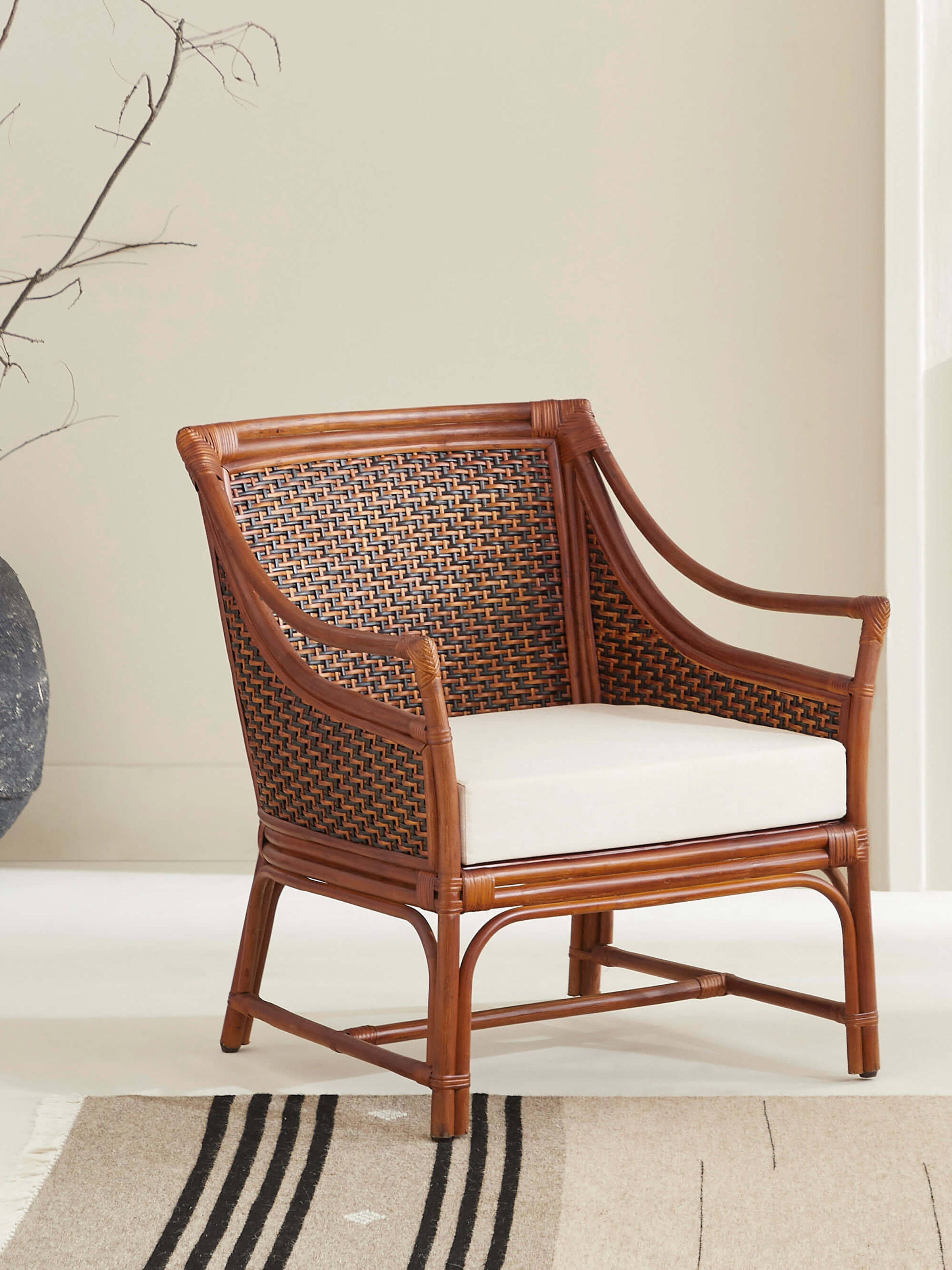 Side view of the upholstered cane and cotton armchair, highlighting its cane backrest and sturdy armrests.