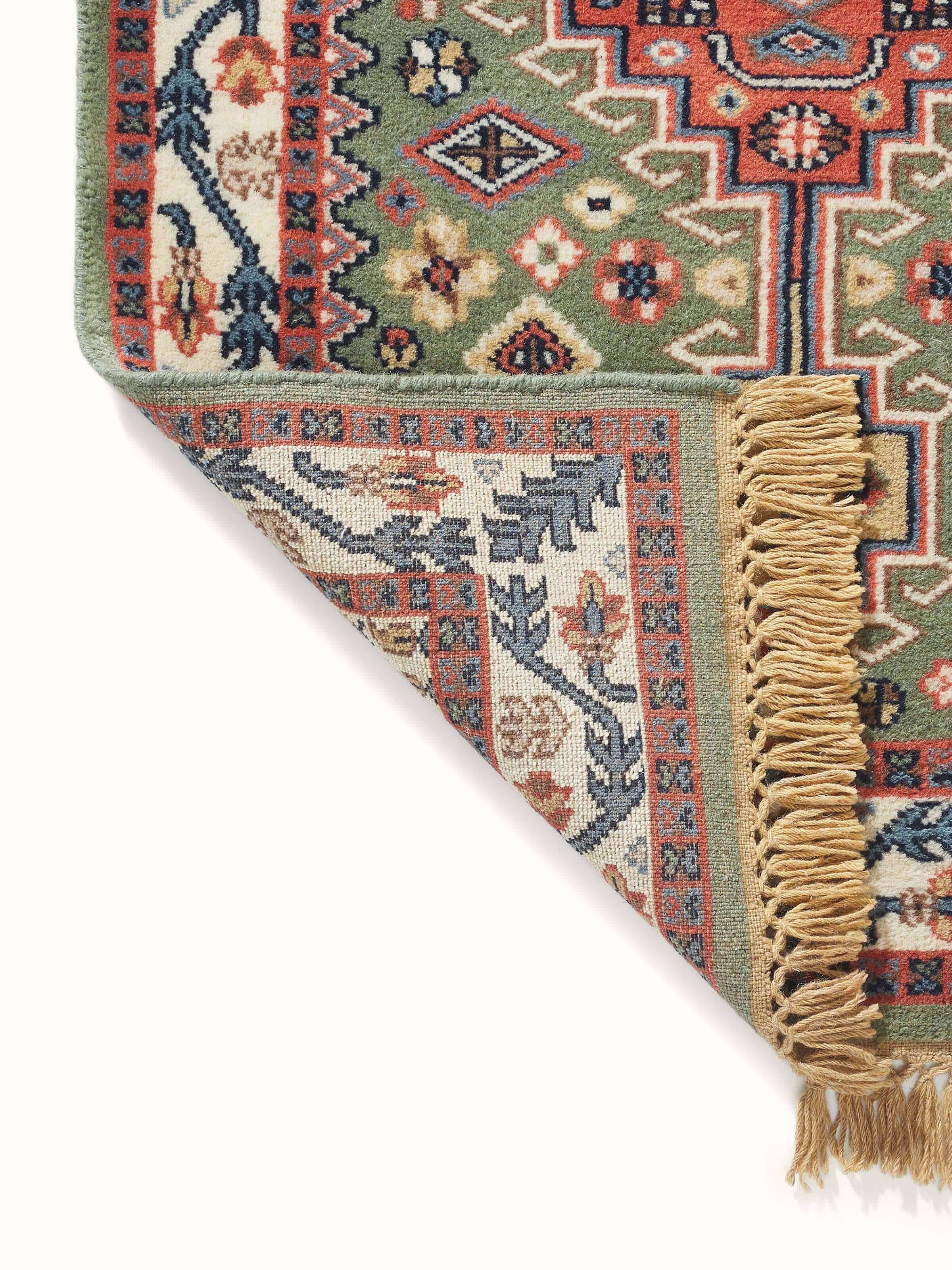 Full view of Persian Kazak light green Gwalior wool hand-knotted runner displayed on a floor, highlighting its length and overall design