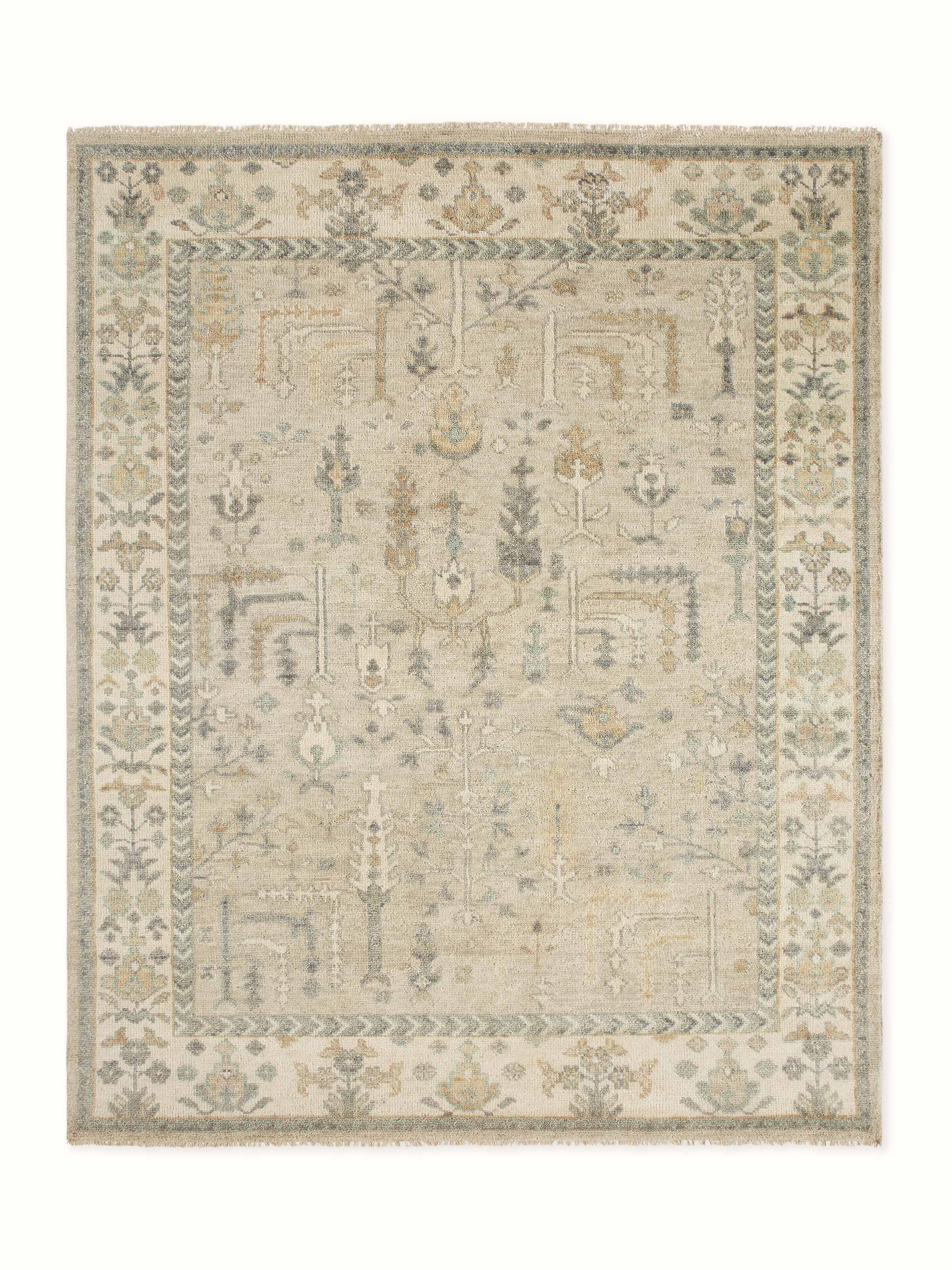 Angled close-up showing the traditional Oushak floral motifs in grey and green on hand-knotted Bhadohi wool