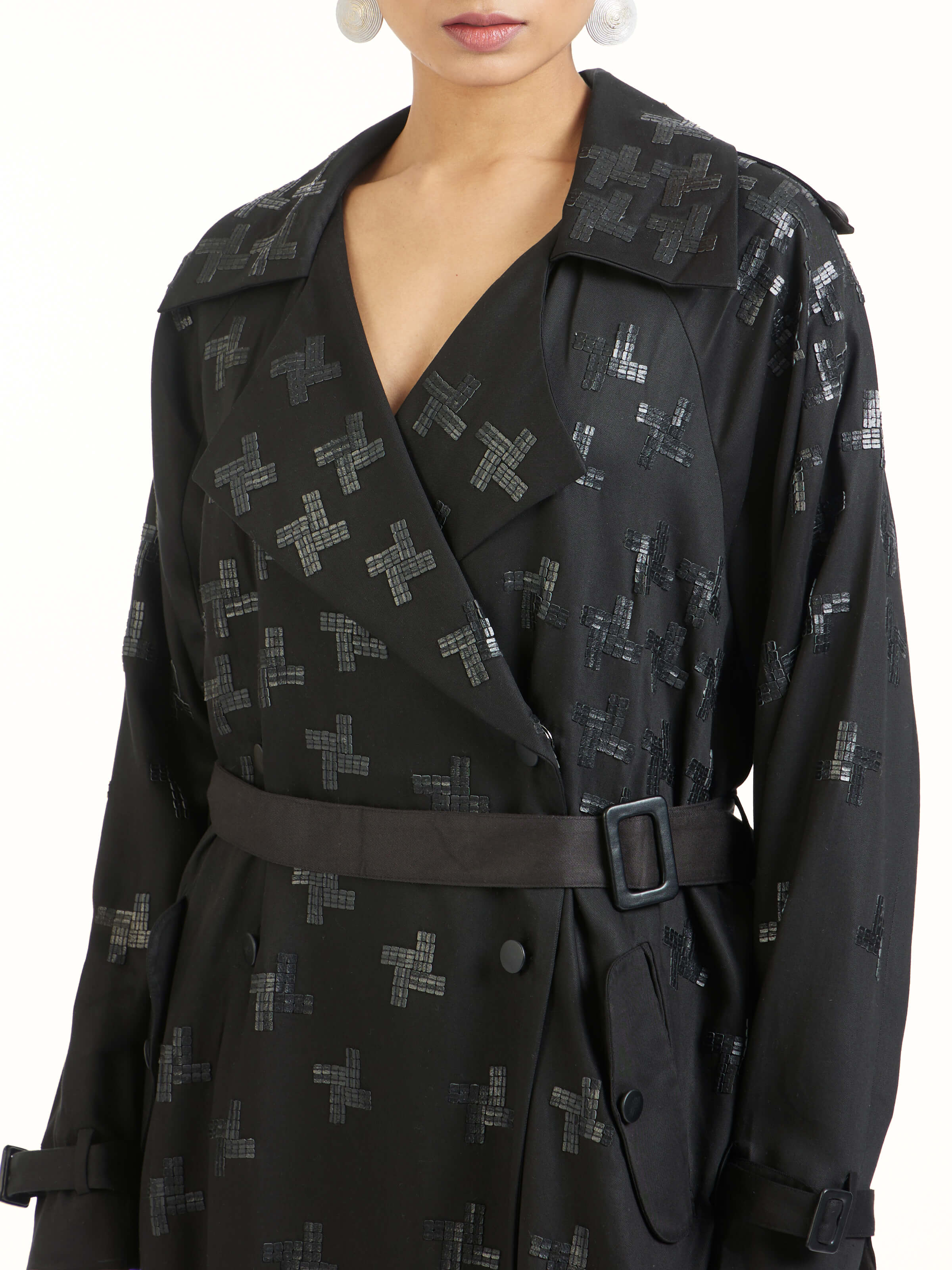 Detail view of black hand embroidered houndstooth sequin trenchcoat showing sequin and stitch work