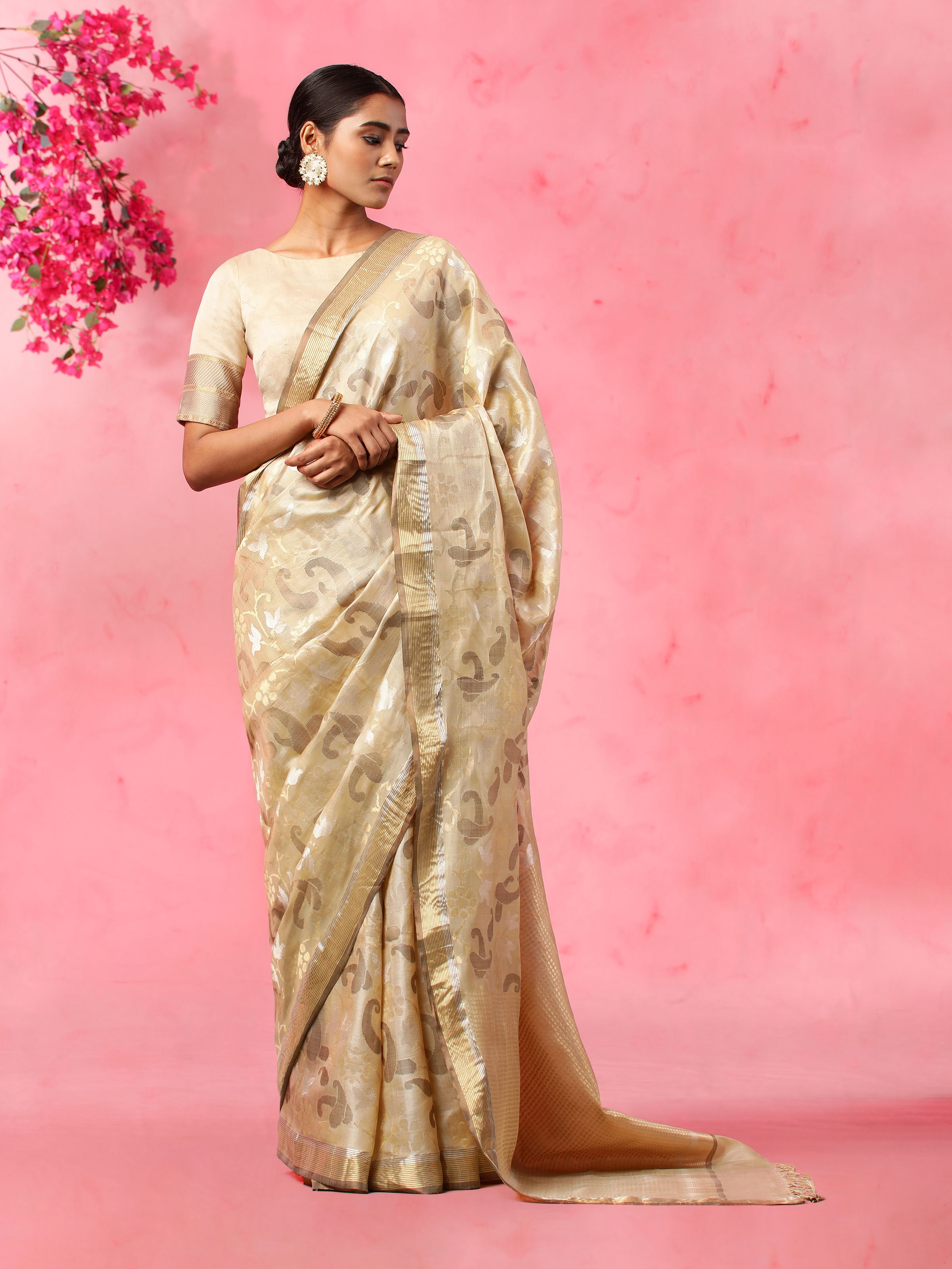 Lifestyle shot of beige tussar silk saree draped elegantly on model in natural light