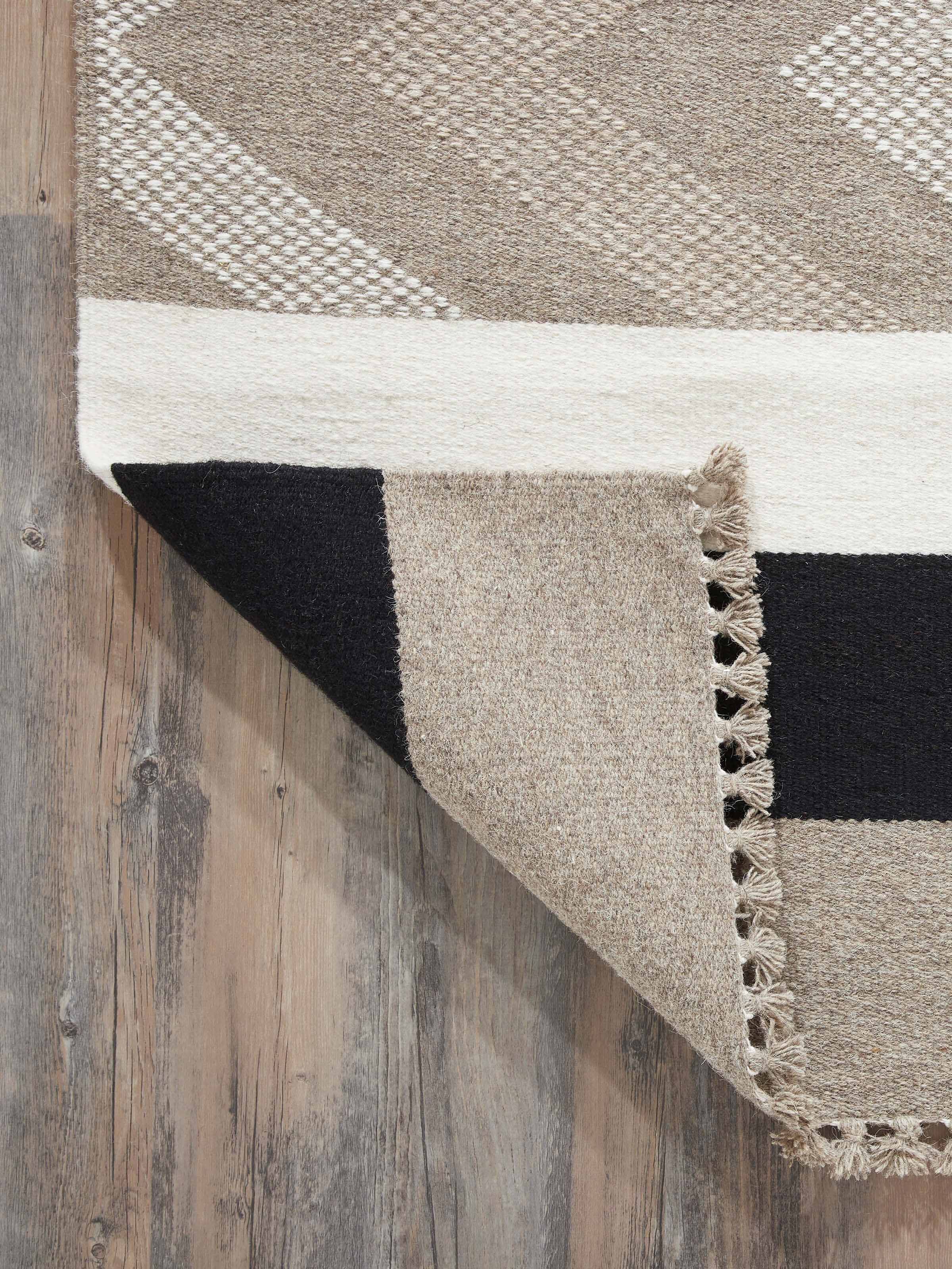 Side view of Textured Chevron Grey Melange Jawaja wool & cotton handloom dhurrie (4x6 ft), demonstrating its thickness and texture.