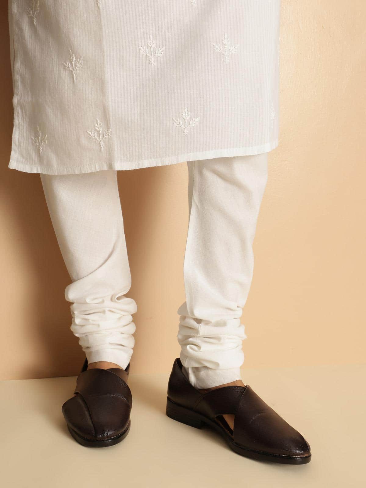 Full-length lifestyle shot of white churidar styled with kurta, highlighting fitted silhouette.