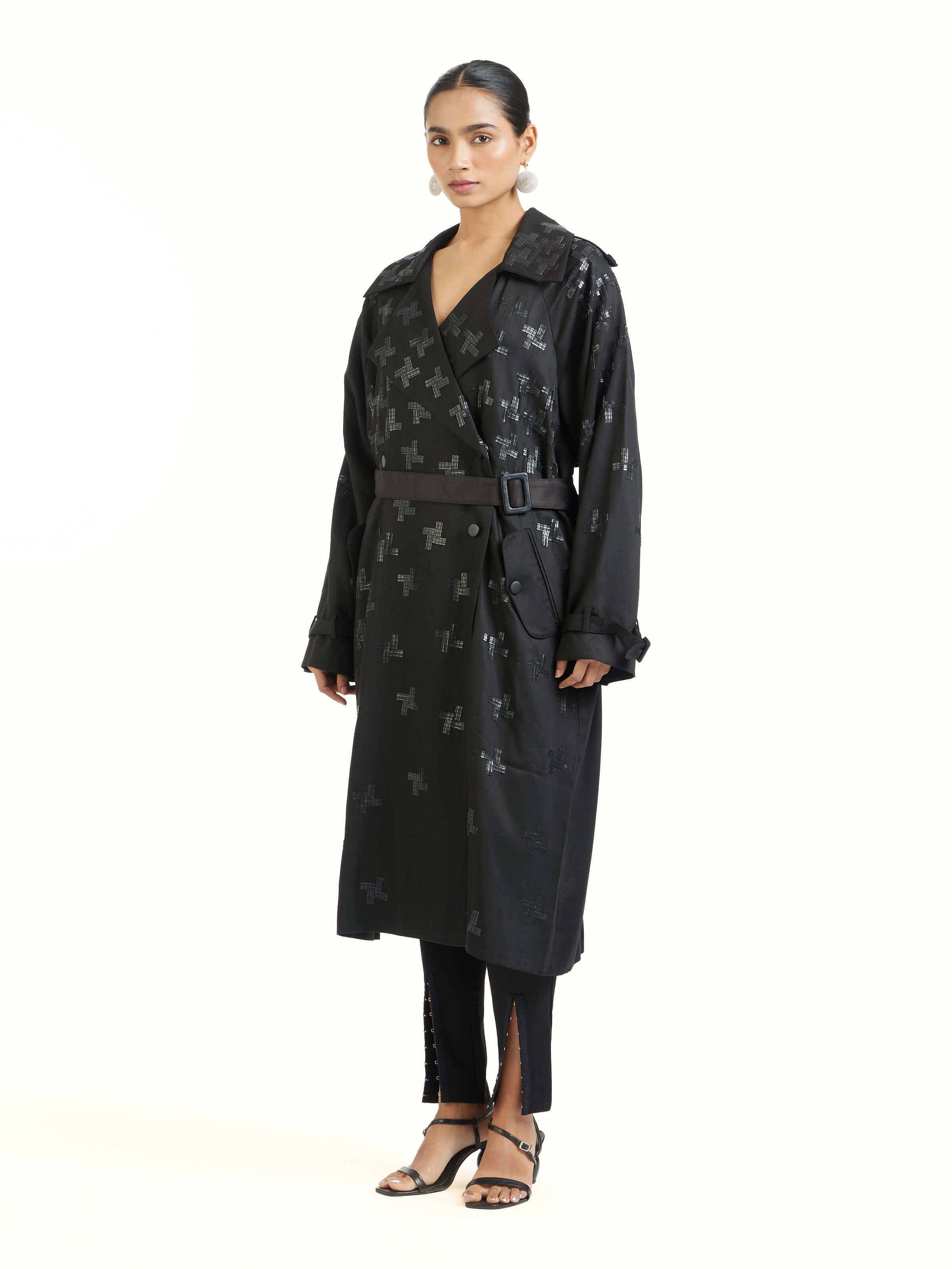 Side view of black hand embroidered houndstooth sequin trenchcoat highlighting structured silhouette