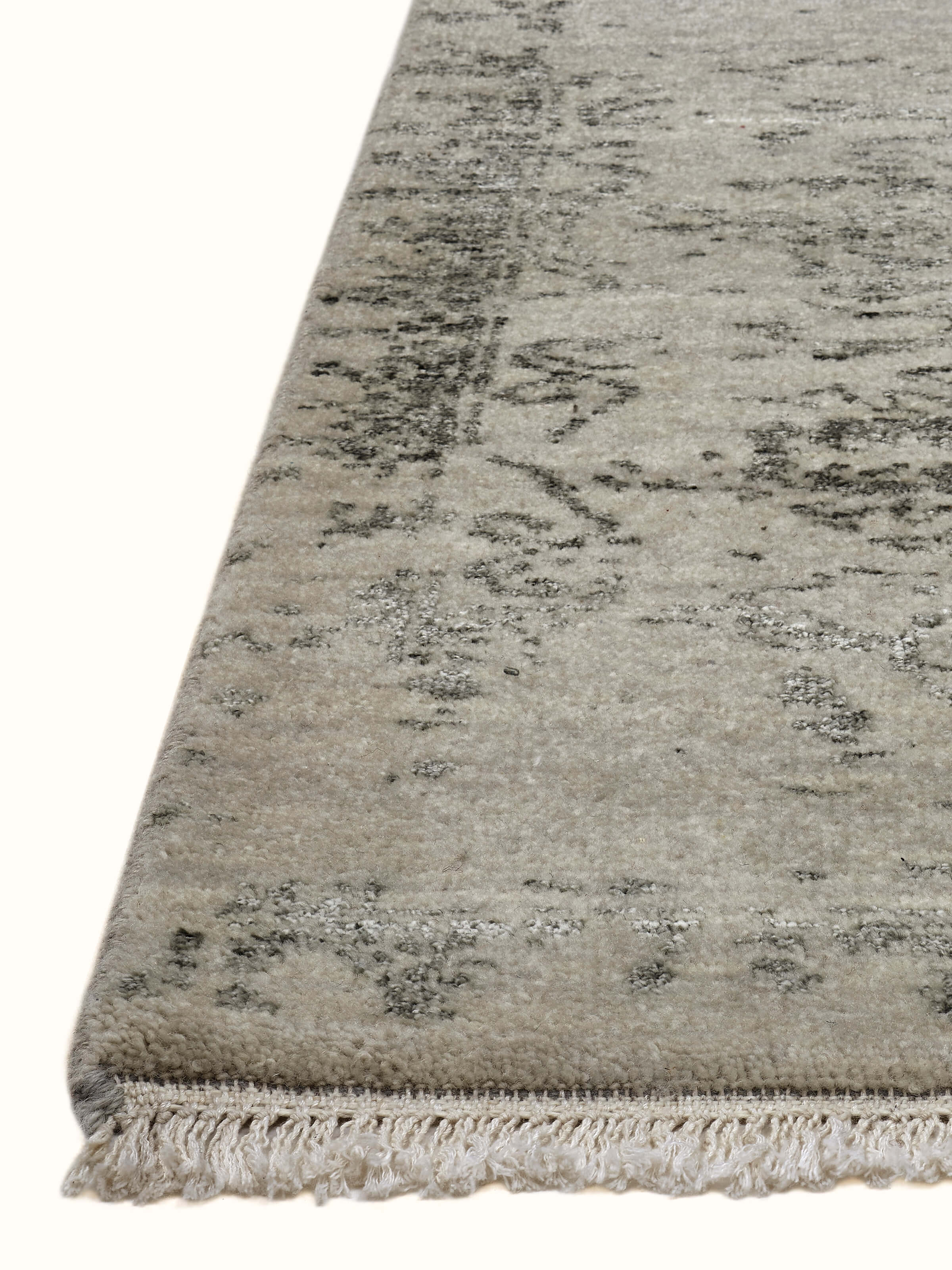 Angled view highlighting faded motif on grey and charcoal Agra transitional rug