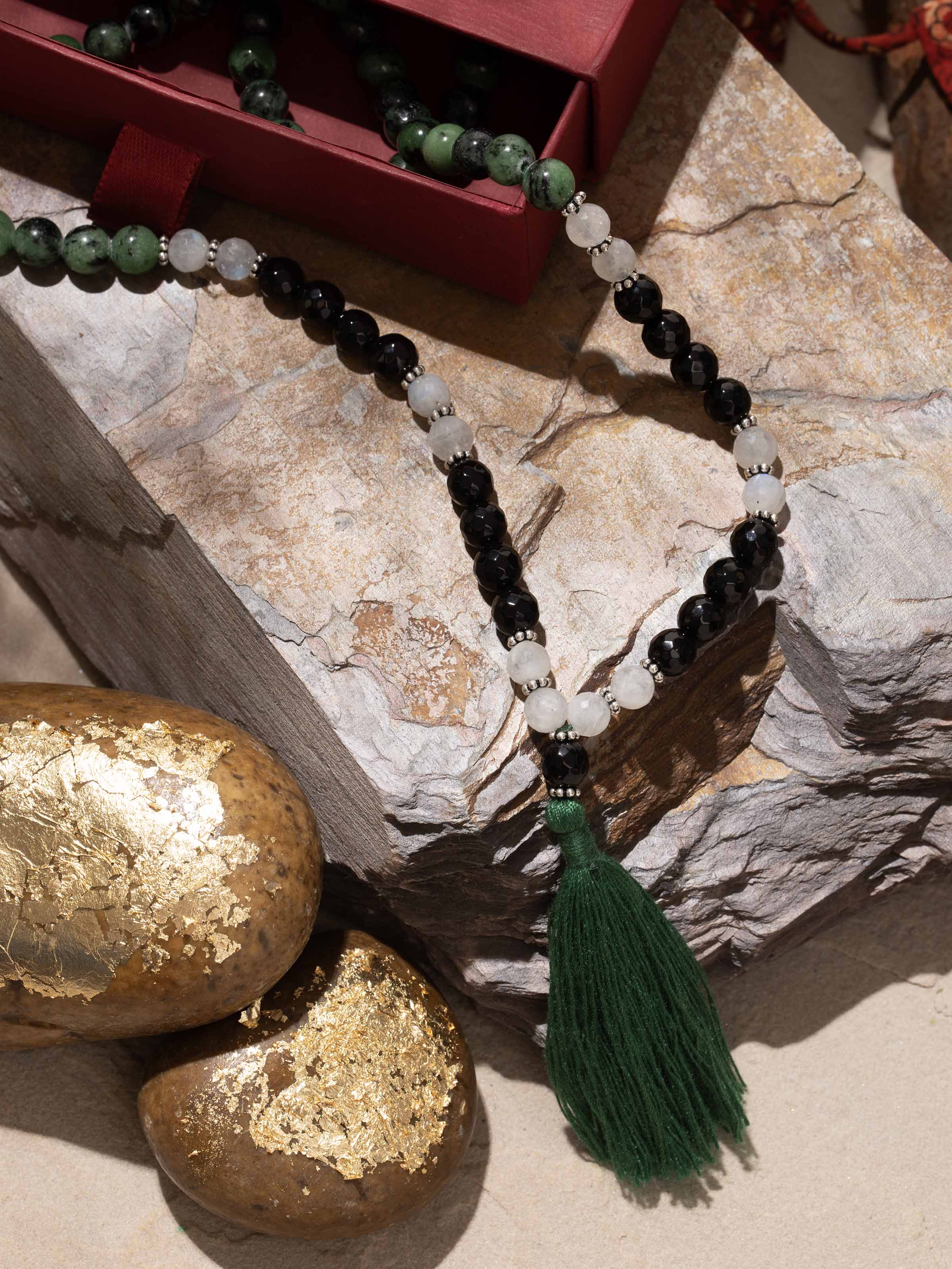 Side view of gemstone mala highlighting contrast between green, black, and white tones