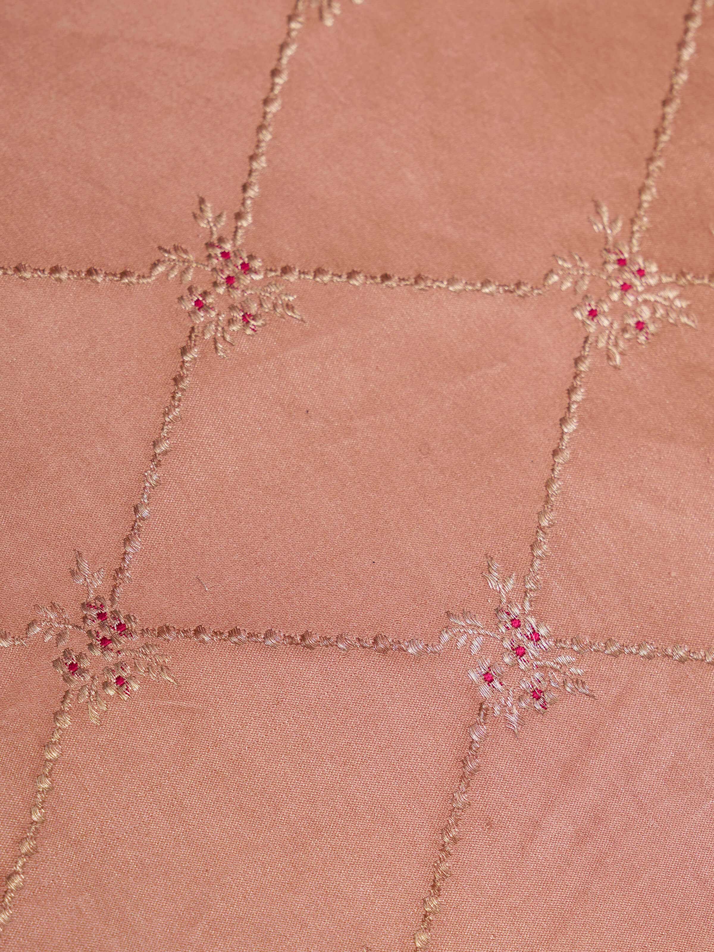 Angled display of Mandana peach silk brocade table mats showcasing fine craftsmanship.
