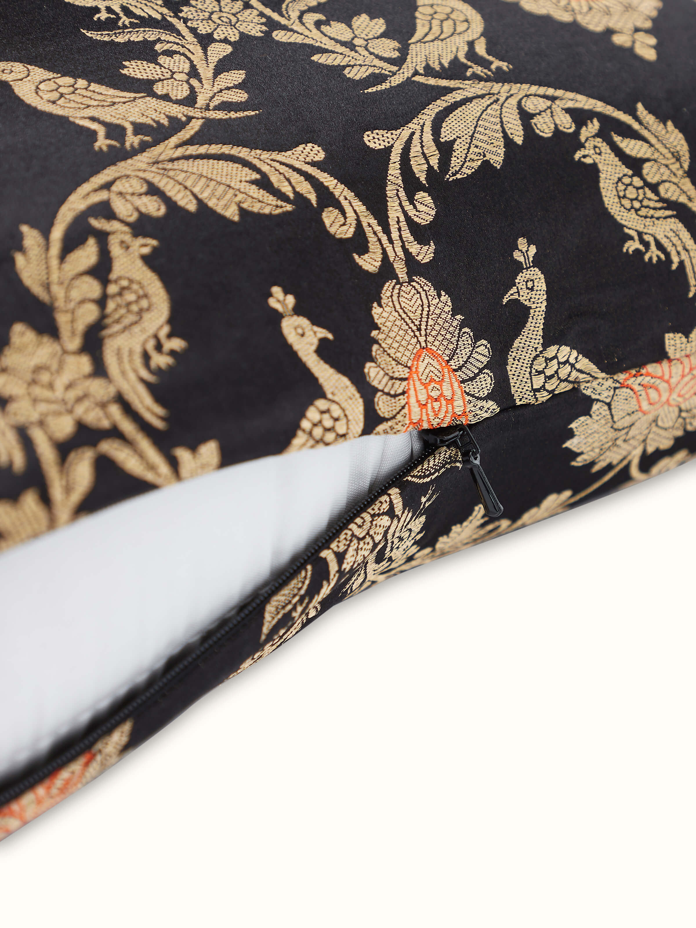 Angled view of cushion showing luminous silk fabric and ornate Banarasi pattern.