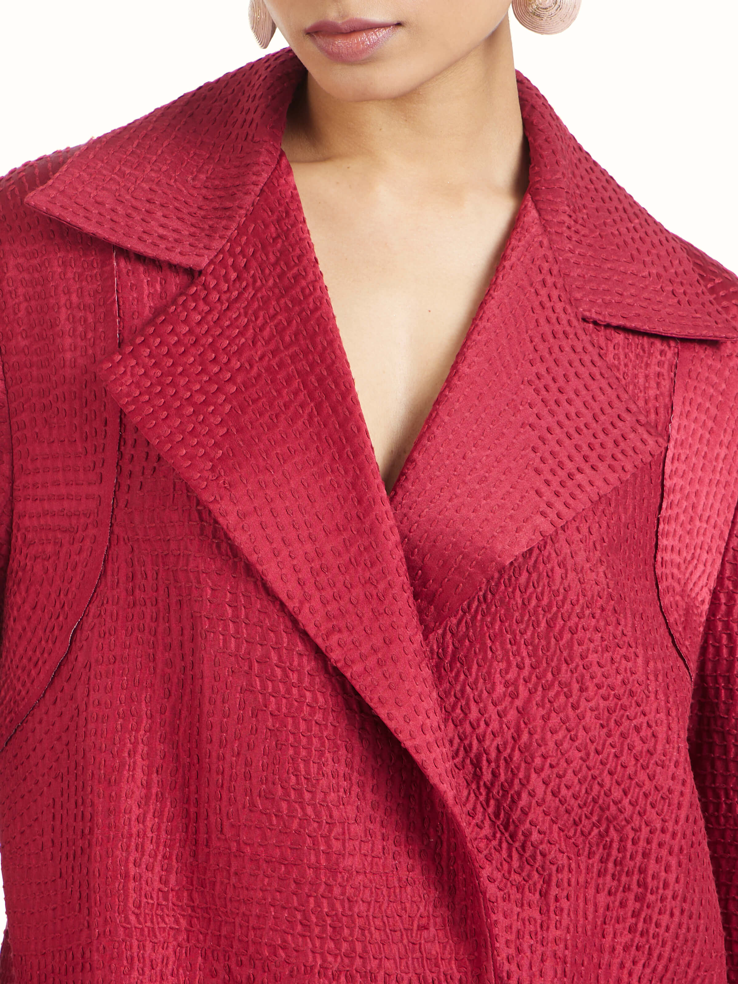 Detail view of red silk kantha trench coat showing silk texture and stitch craftsmanship