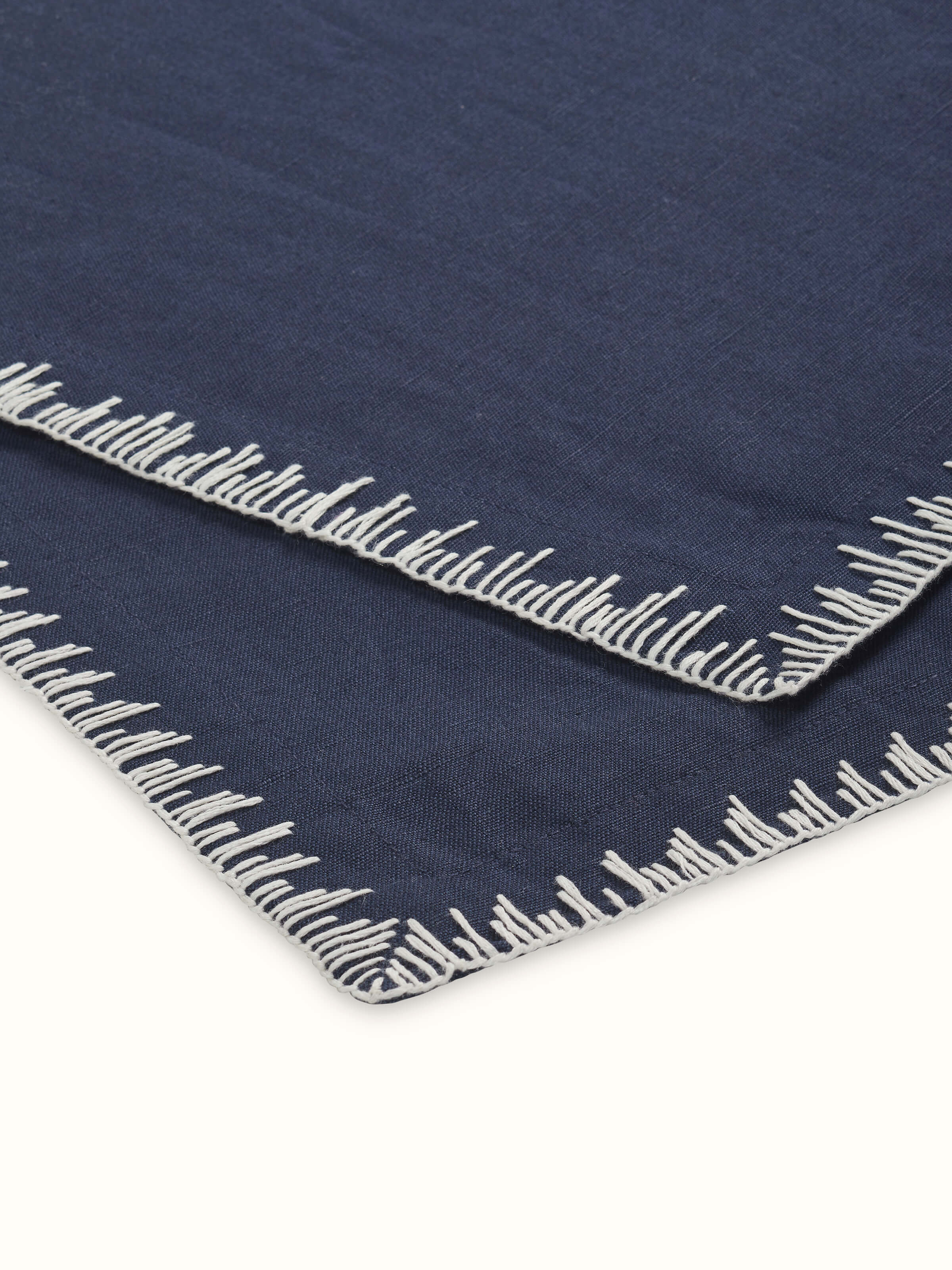 Close-up of hand embroidery and edge stitch detailing on indigo table mat