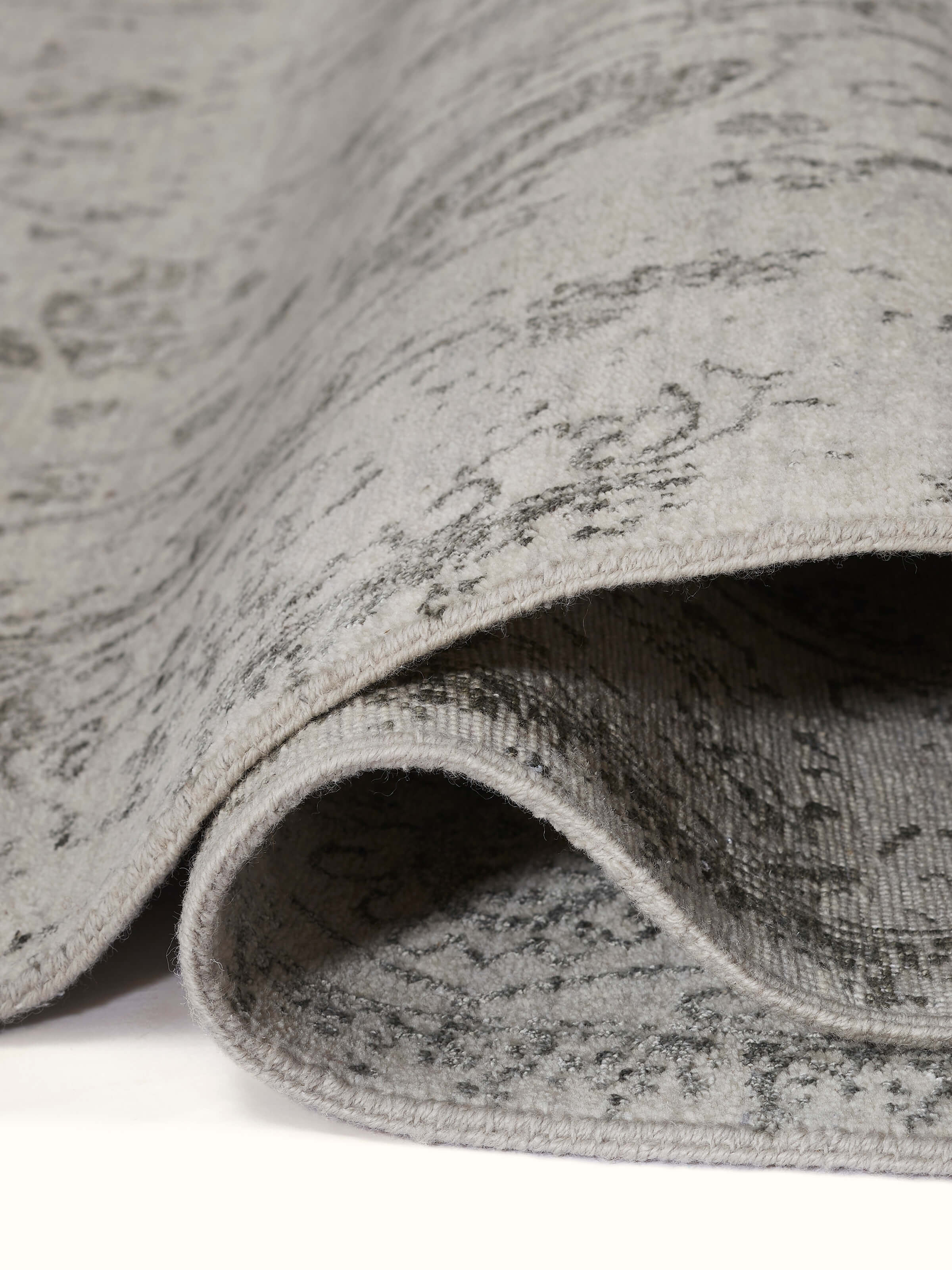 Texture close-up of distressed wool and viscose blend in grey charcoal Agra rug
