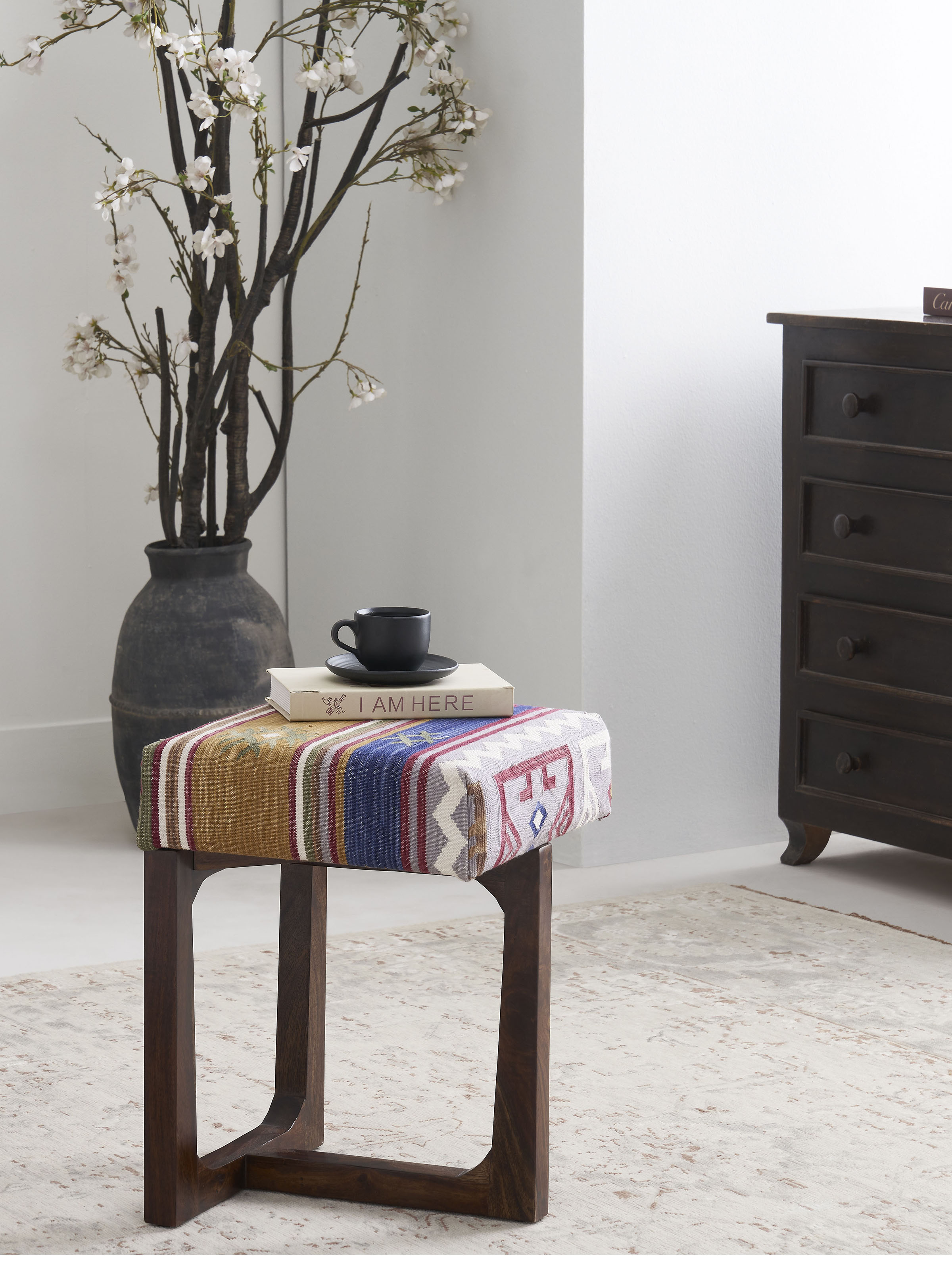 Side view of Panja Dhurrie Upholstered Sheesham Wood Stool featuring vibrant dhurrie fabric and sturdy wood construction.