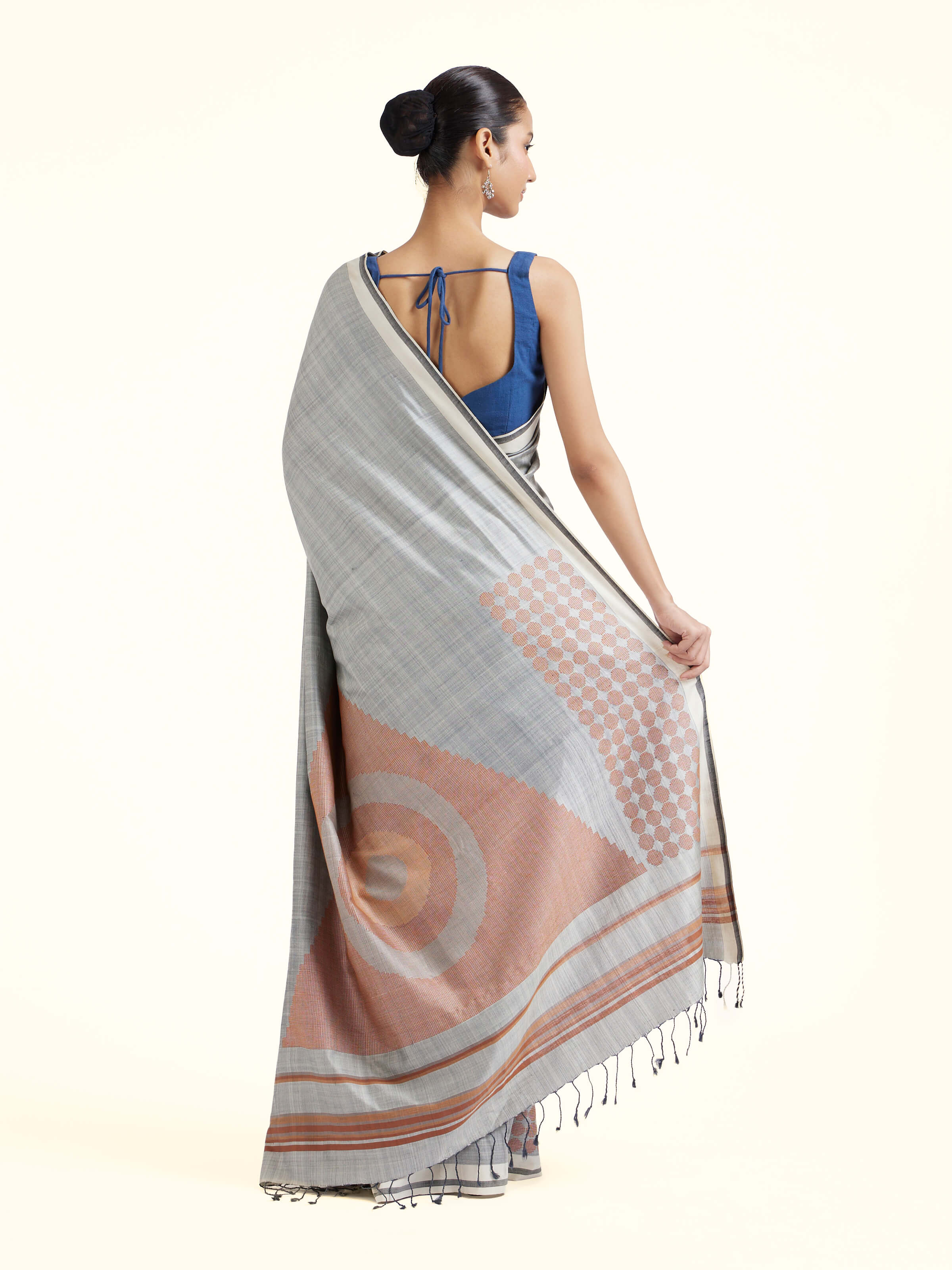 Back view of grey silk extra-weft saree displaying ornate pallu design