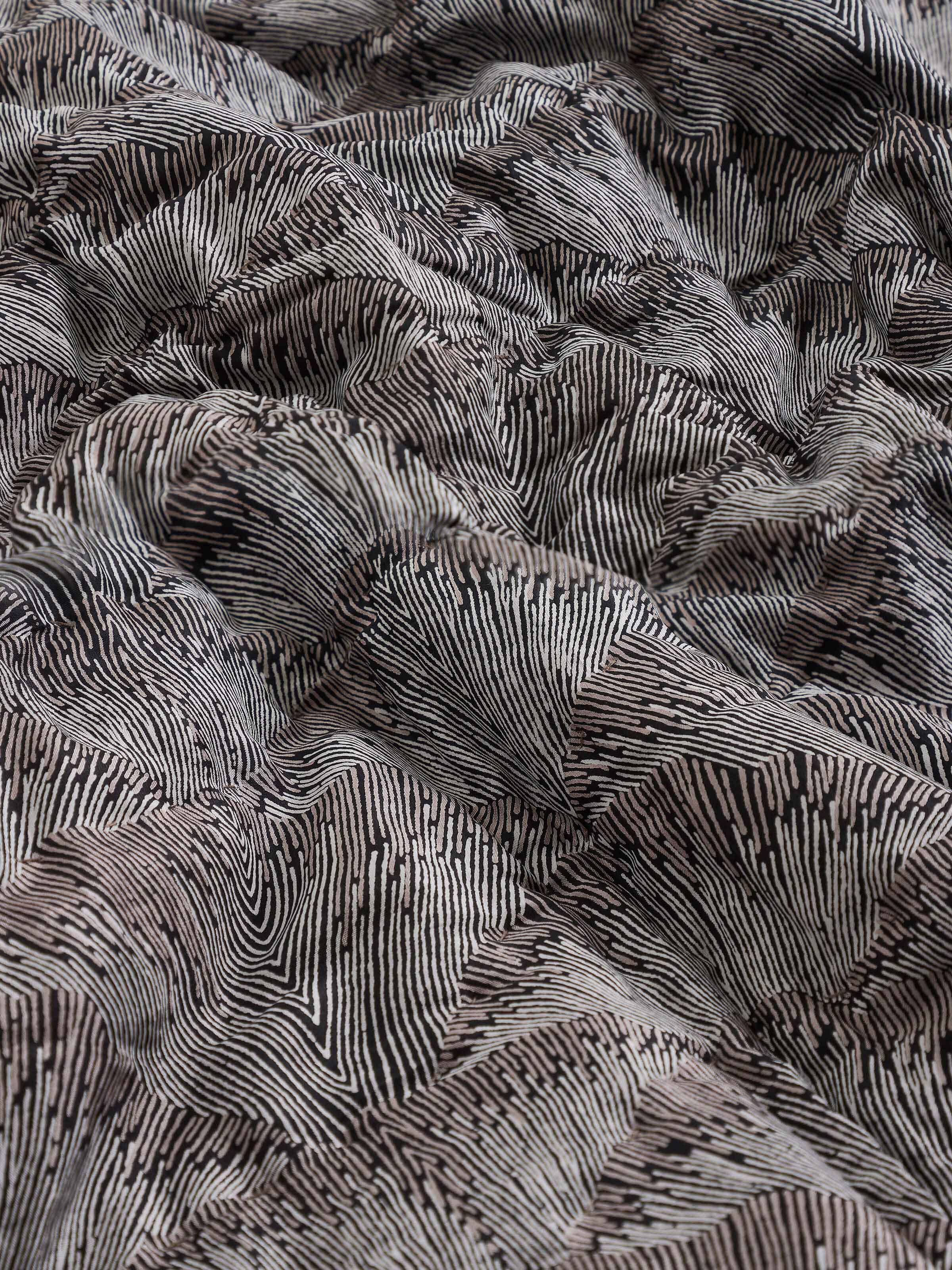 Detail shot of floral block print and textured finish on Parvat brown silk quilt.