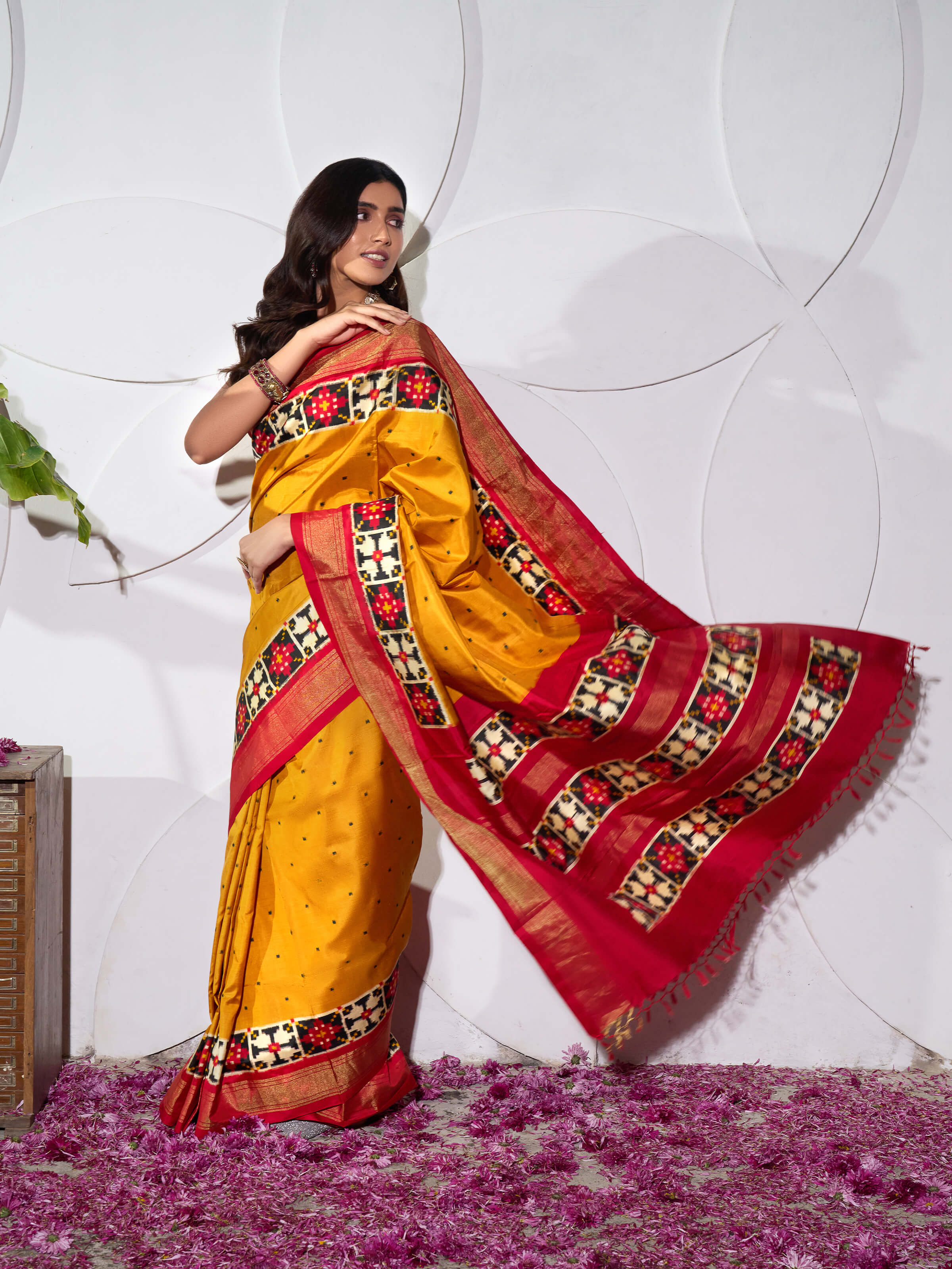 Angled view of yellow silk Pochampally double ikat saree emphasizing pattern alignment