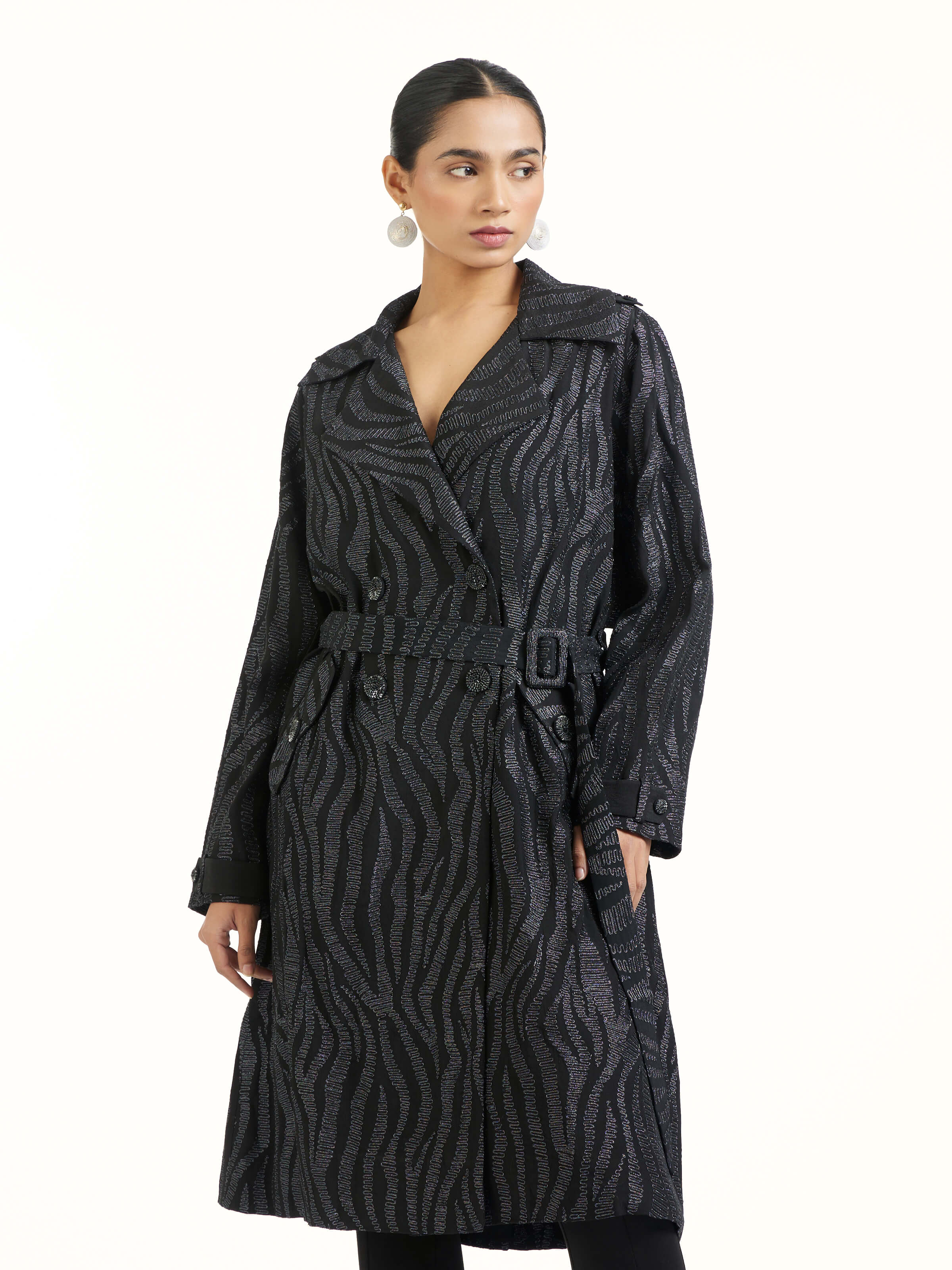 Angled view of black aari hand embroidered trenchcoat emphasizing handcrafted aari work