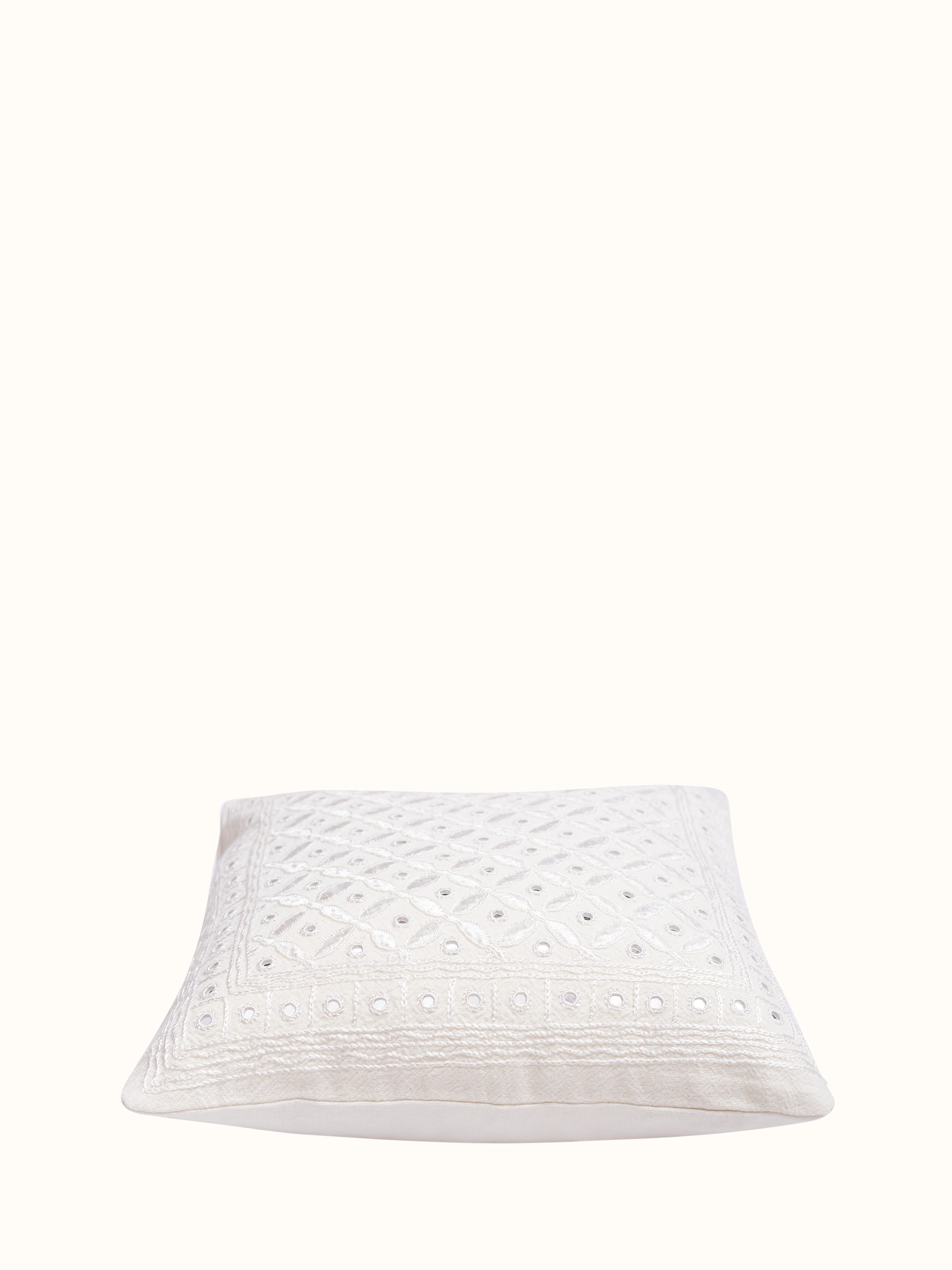 Angled view of Lippan white Pakko embroidered cotton cushion cover