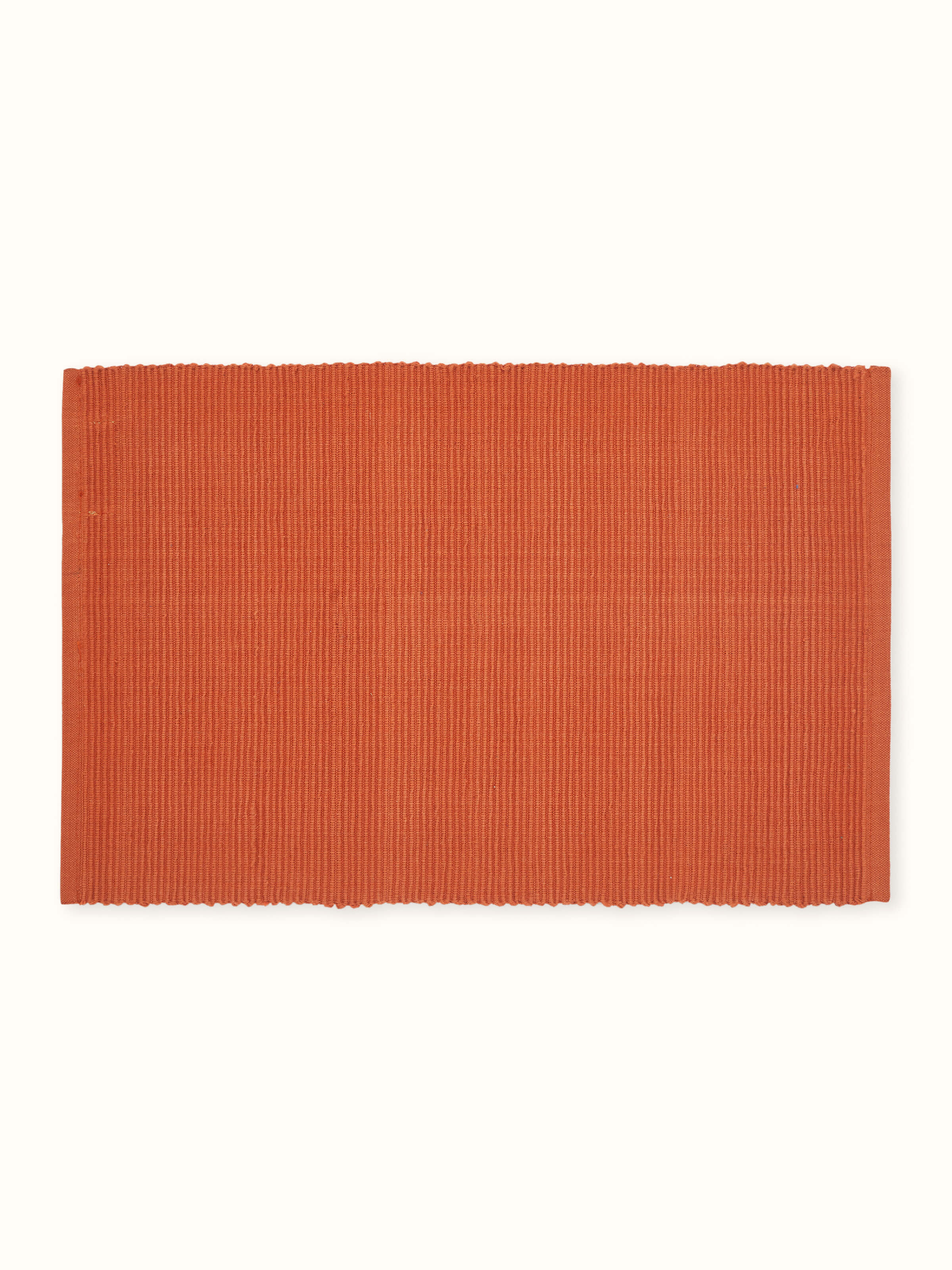 Angled view displaying the warm rust solid color and handloom texture of the cotton table mats