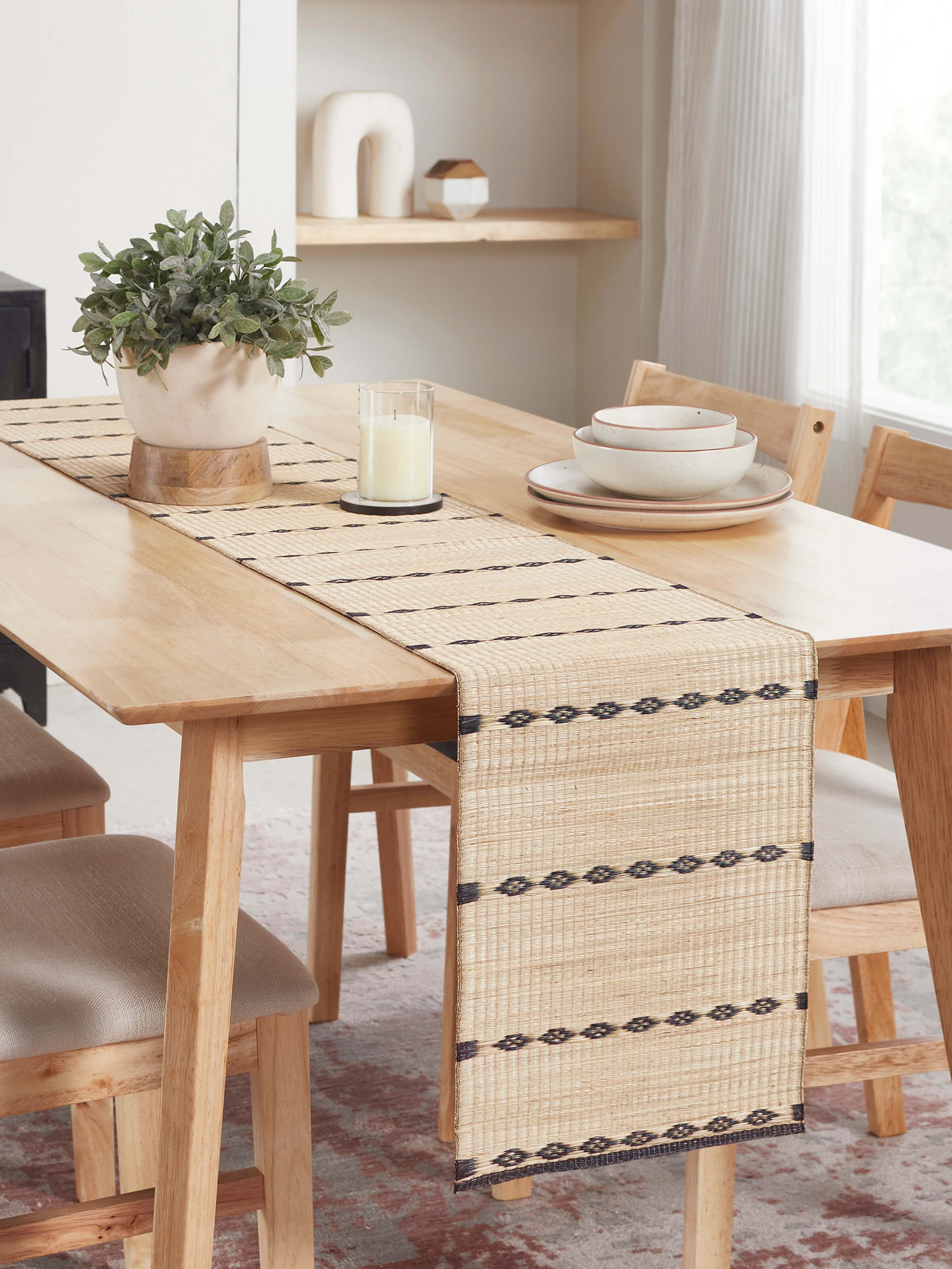 Lifestyle view of Prakriti black stripe Madurkathi table runner on dining table, highlighting its earthy texture and natural finish.
