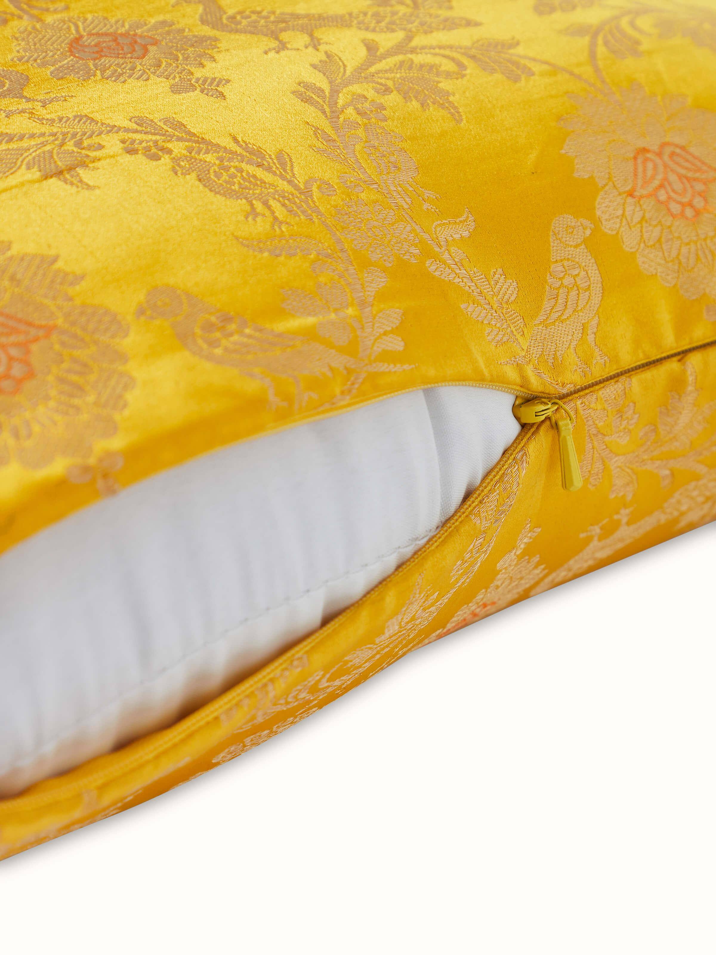 Angled view of cushion highlighting gleaming silk texture and golden motifs.