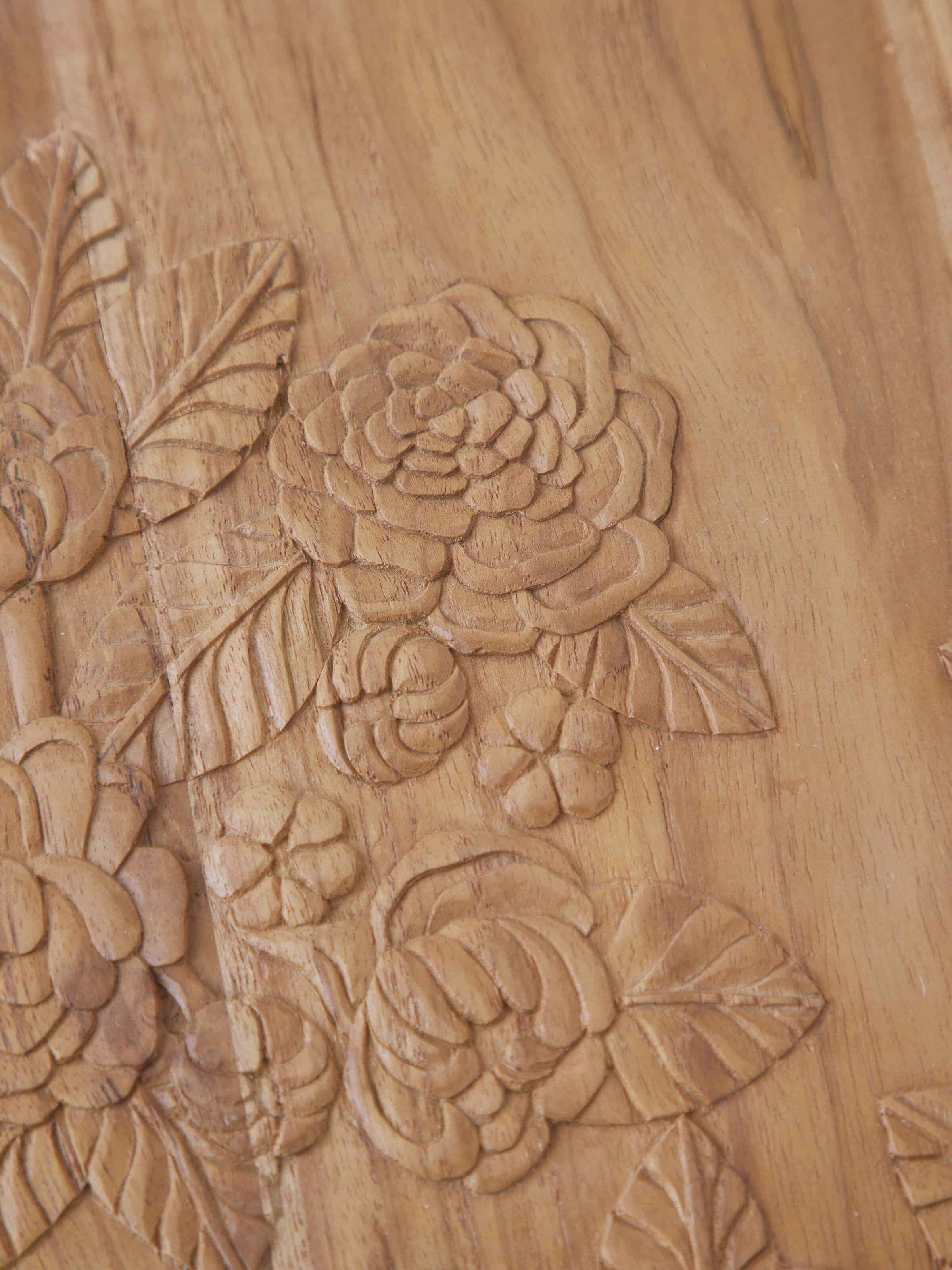 Close-up of the carved patterns on the teak wood round side table, showcasing the quality of the craftsmanship