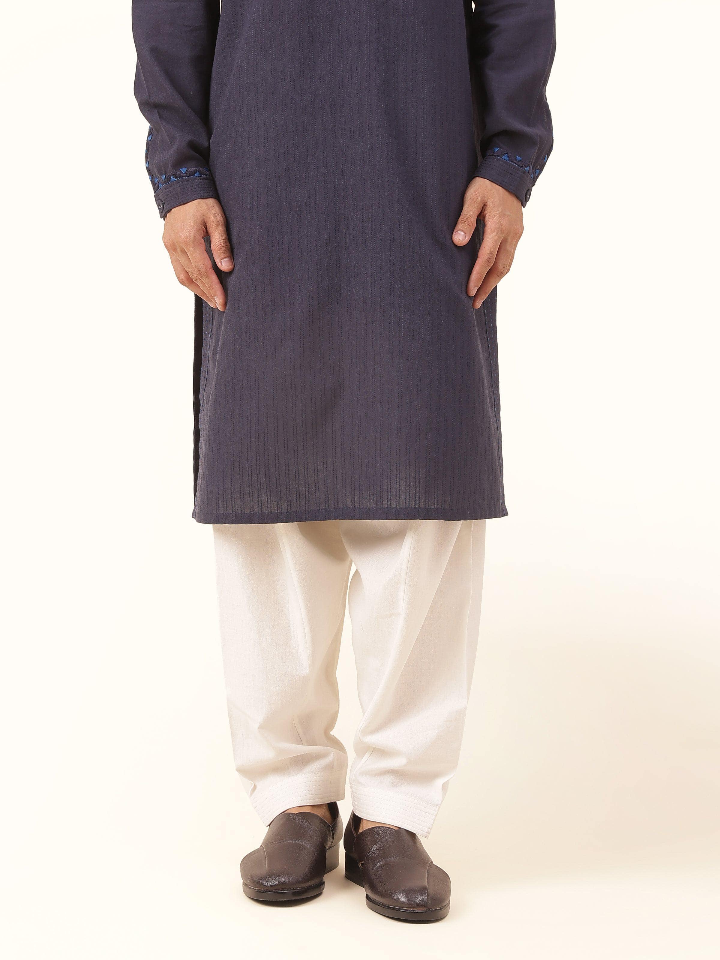 Front view of off-white cotton salwaar featuring pleated waist and classic tapered fit