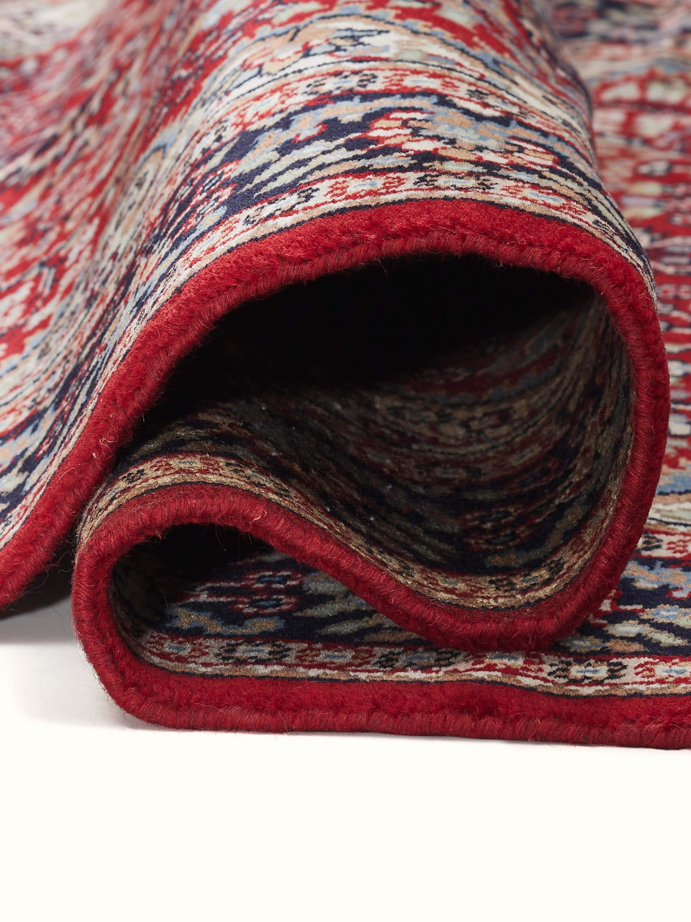 Side angle of traditional red Gwalior wool rug showcasing detailed weaving