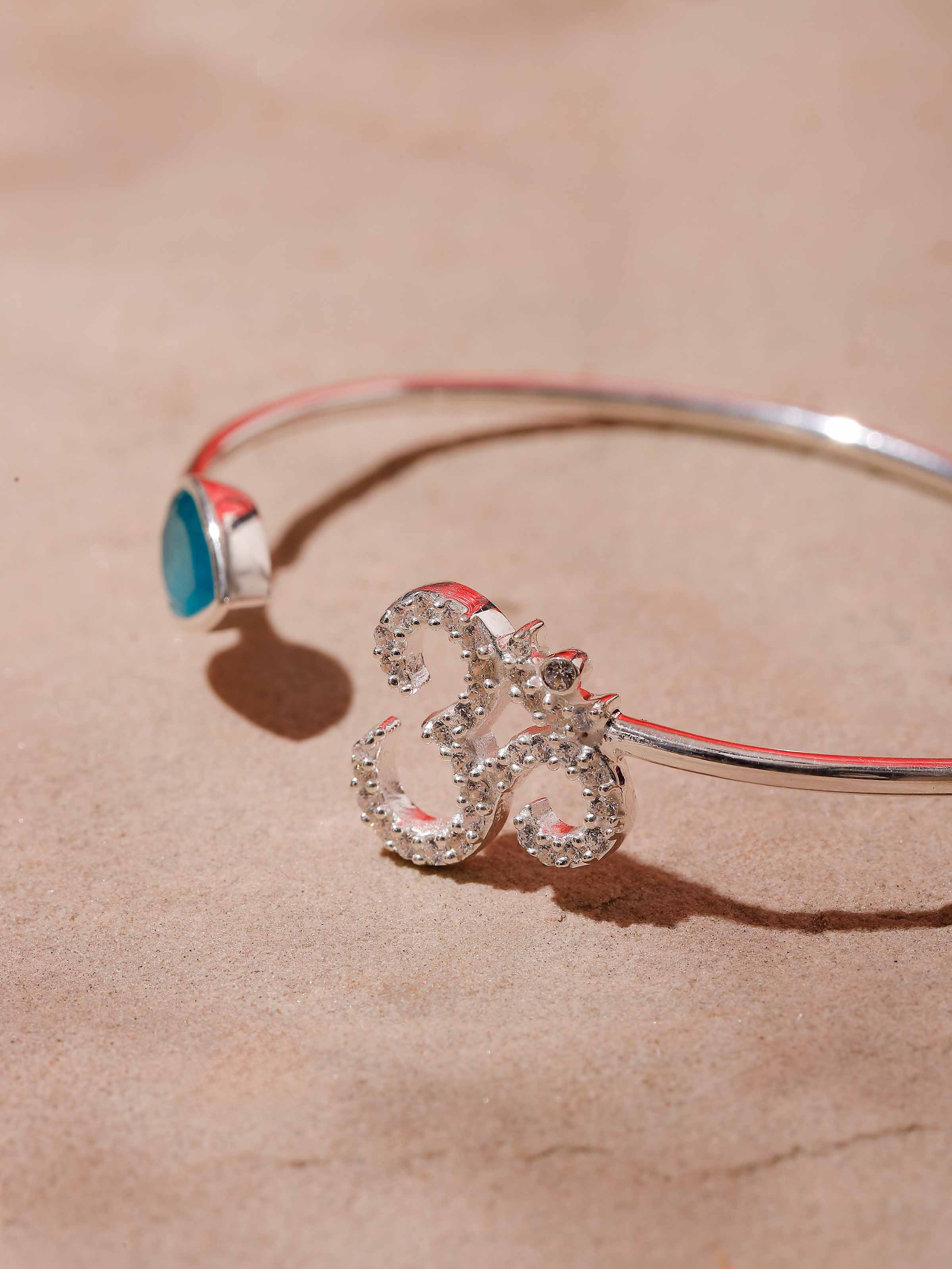 Detailed close-up of bracelet showing silver Om charm and polished jade beads in natural lighting