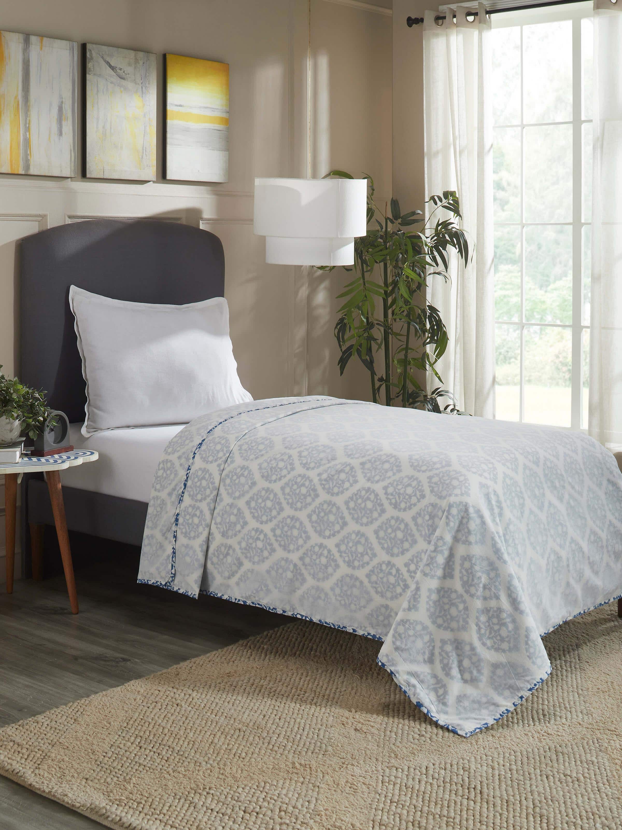 Lifestyle shot of printed dohar draped on a bed, showcasing soft cotton texture and traditional pattern.