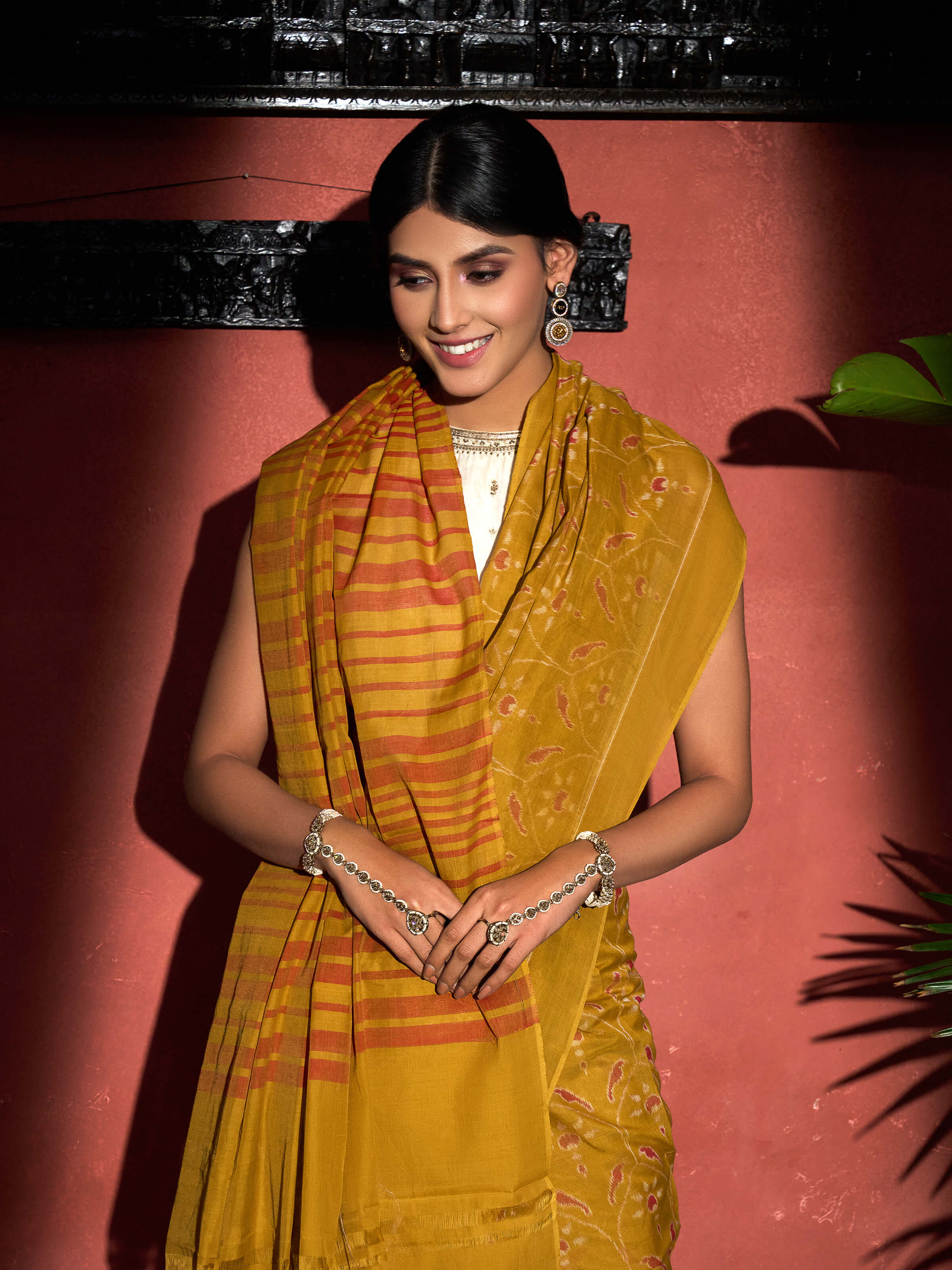 Angled view of mustard cotton Odisha ikat bandha saree highlighting ikat bandha motifs