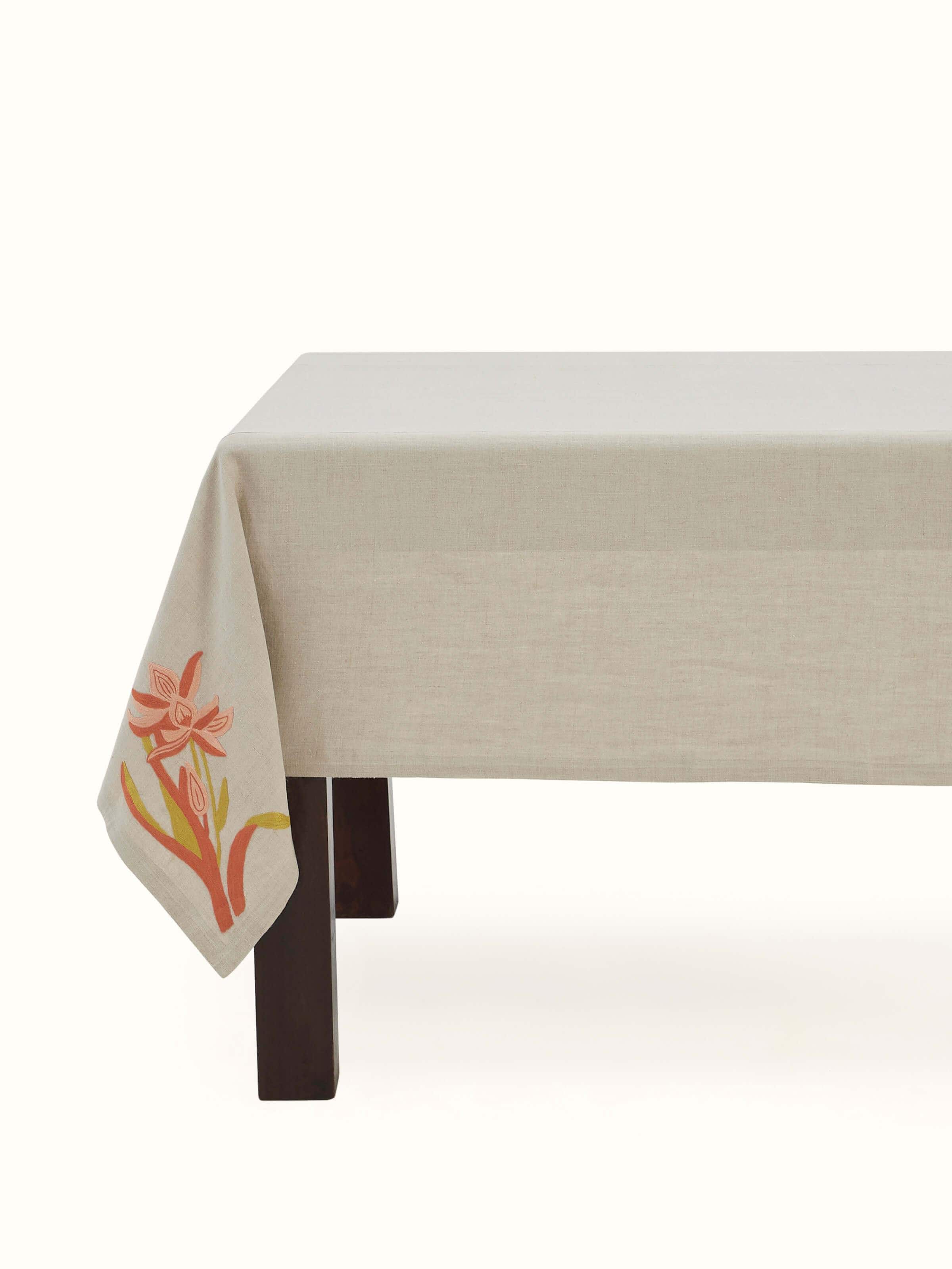 Angled close-up showing intricate floral chain stitch embroidery on beige linen fabric