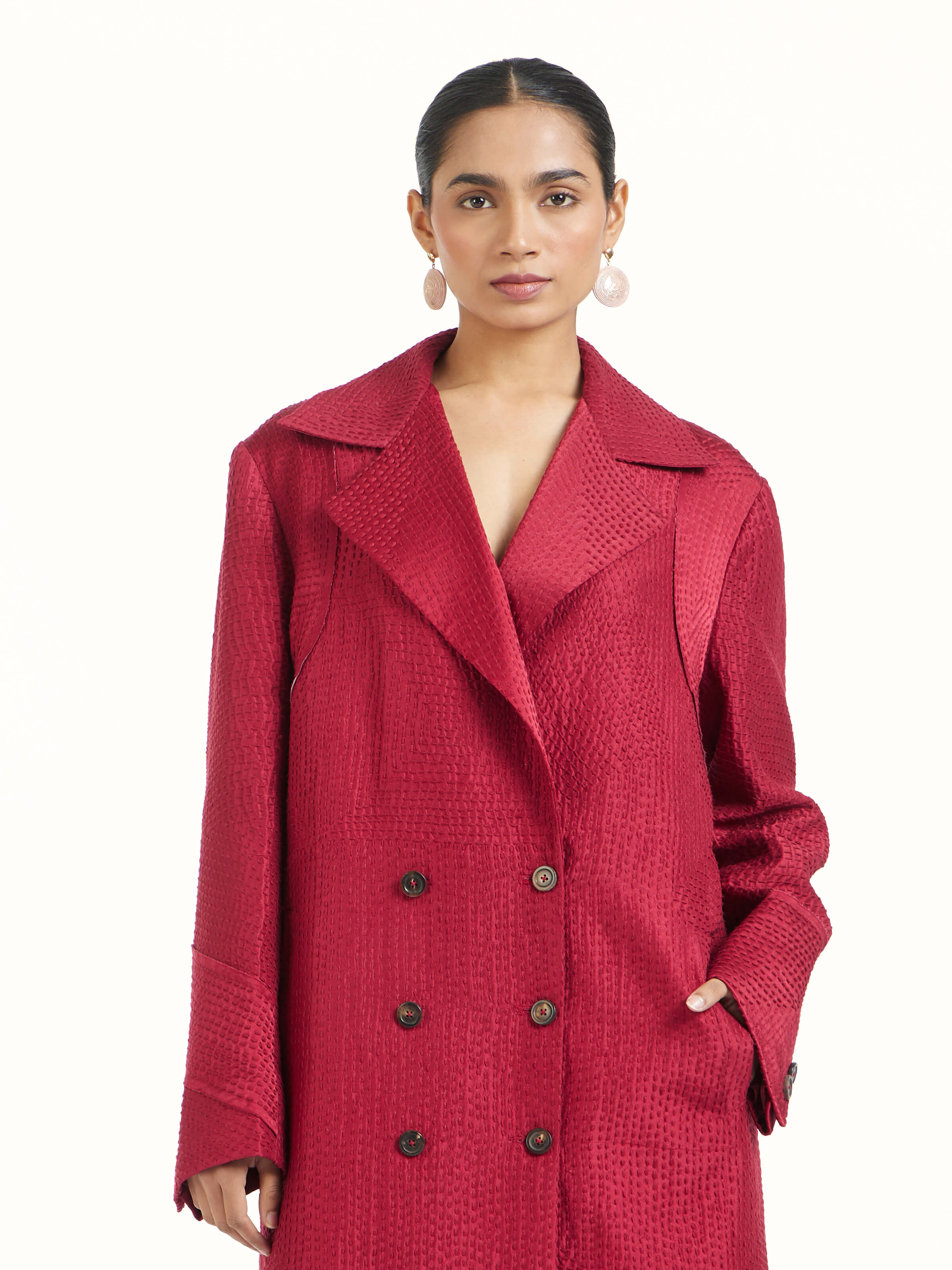 Angled view of red silk kantha trench coat emphasizing handcrafted embroidery details