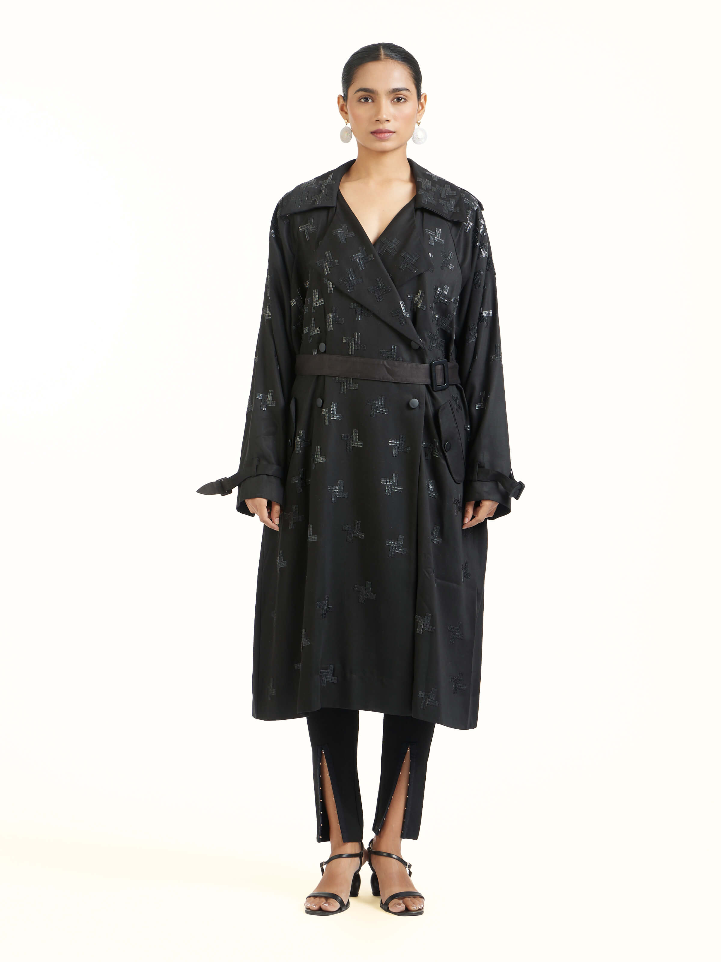 Front view of black hand embroidered houndstooth sequin trenchcoat showcasing detailed embroidery