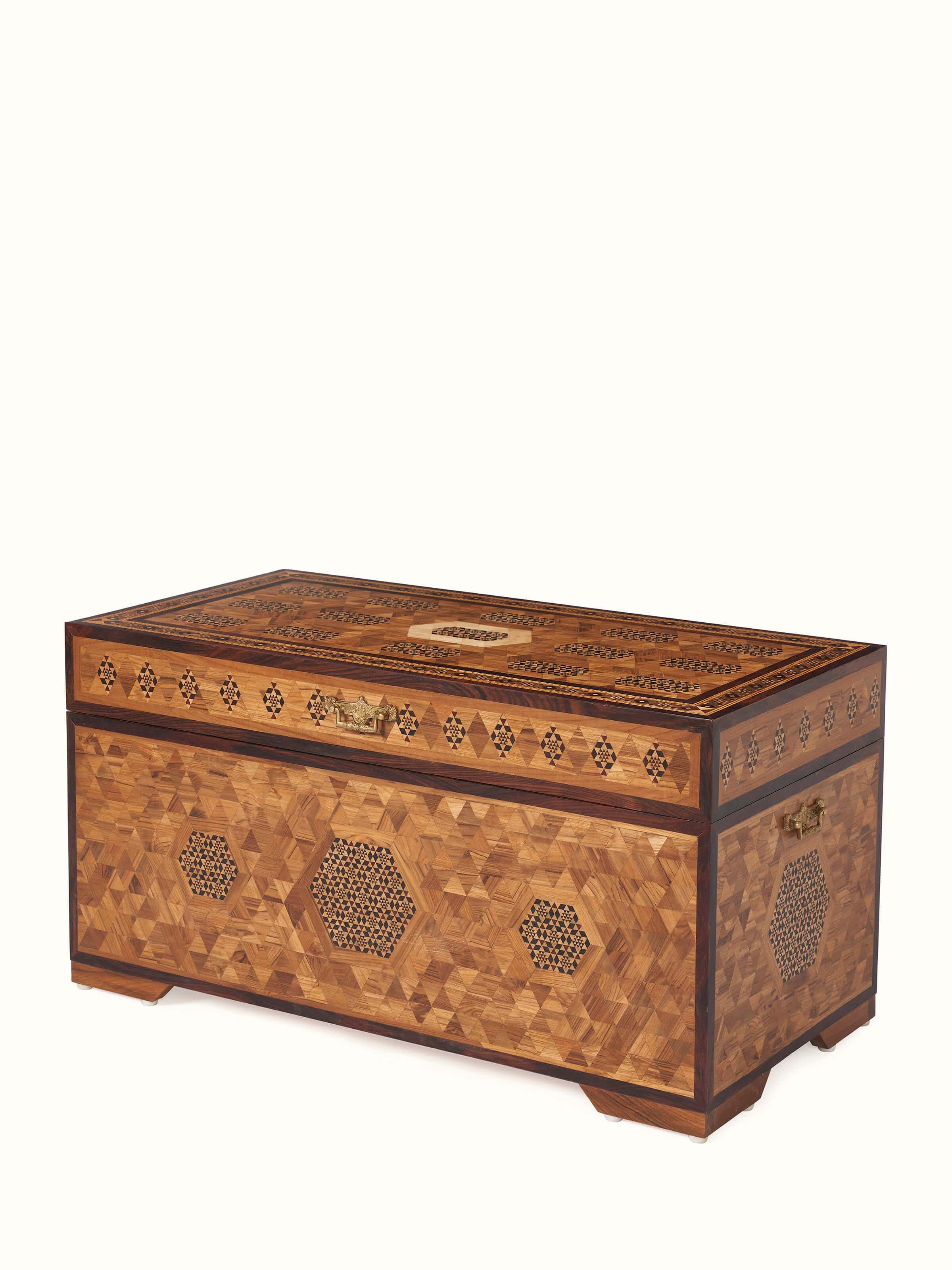 Angled view of teak wood marquetry trunk, highlighting the detailed wood inlay patterns and its sturdy construction.