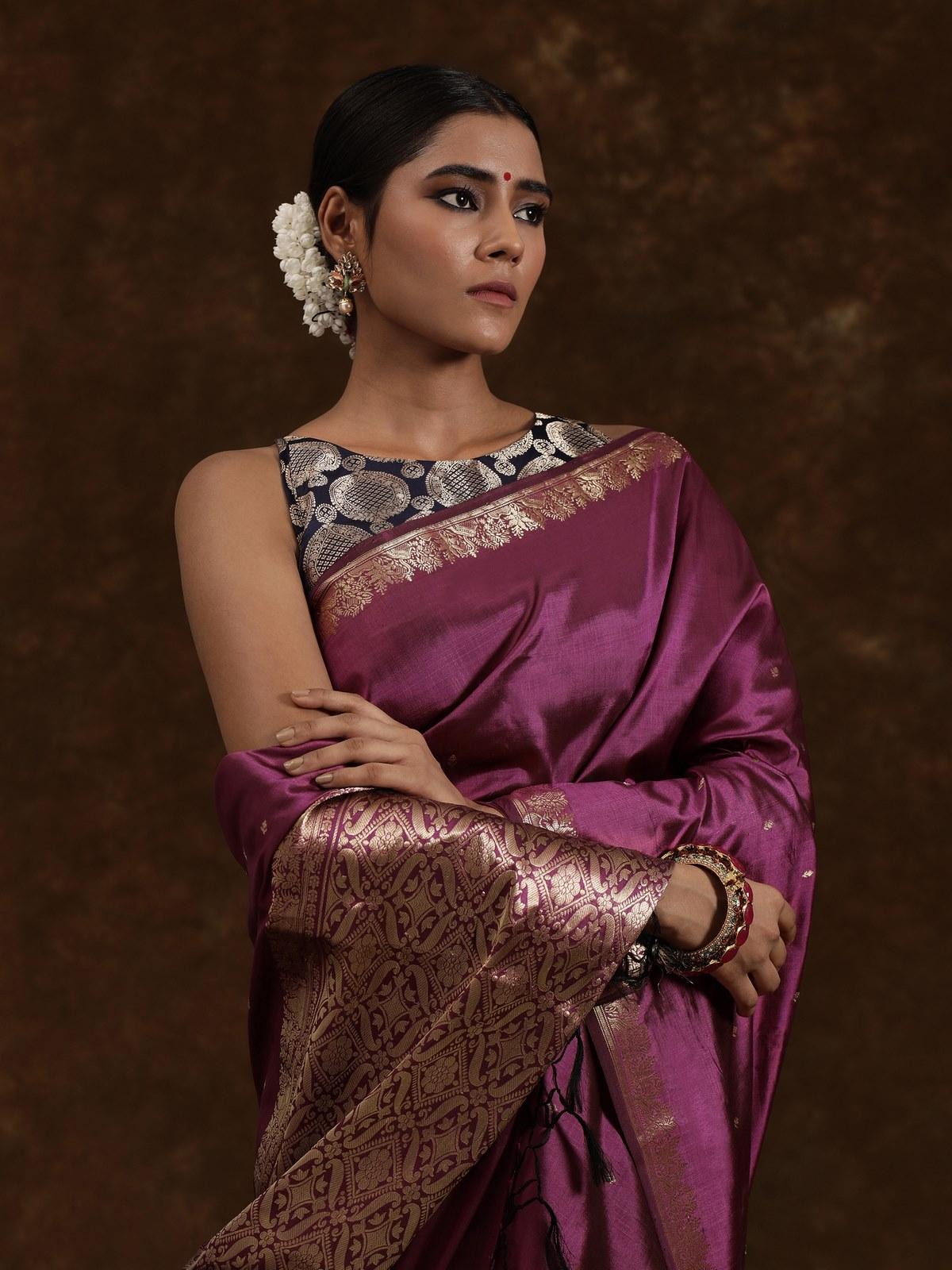 Close-up of Banarasi saree revealing fine zari weave on purple silk base.